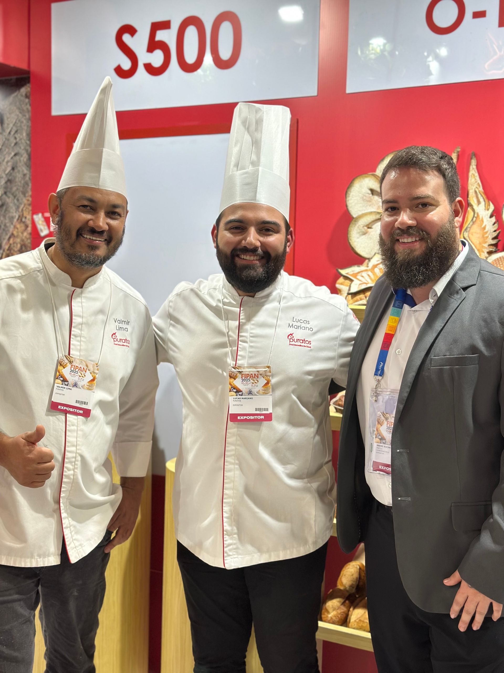 Três homens estão posando para uma foto em frente a uma placa que diz $ 500