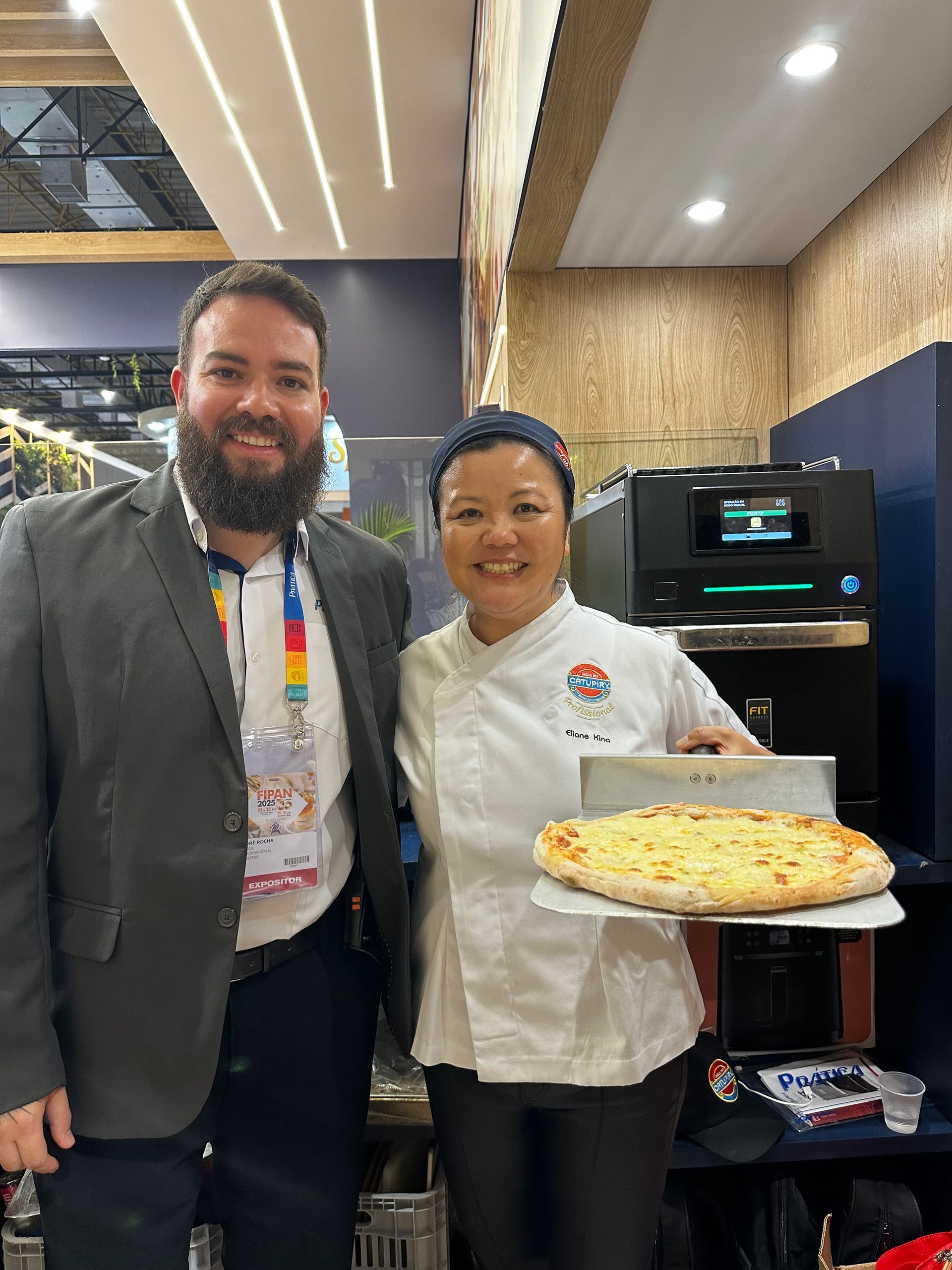 Um homem e uma mulher estão de pé um ao lado do outro segurando uma pizza.