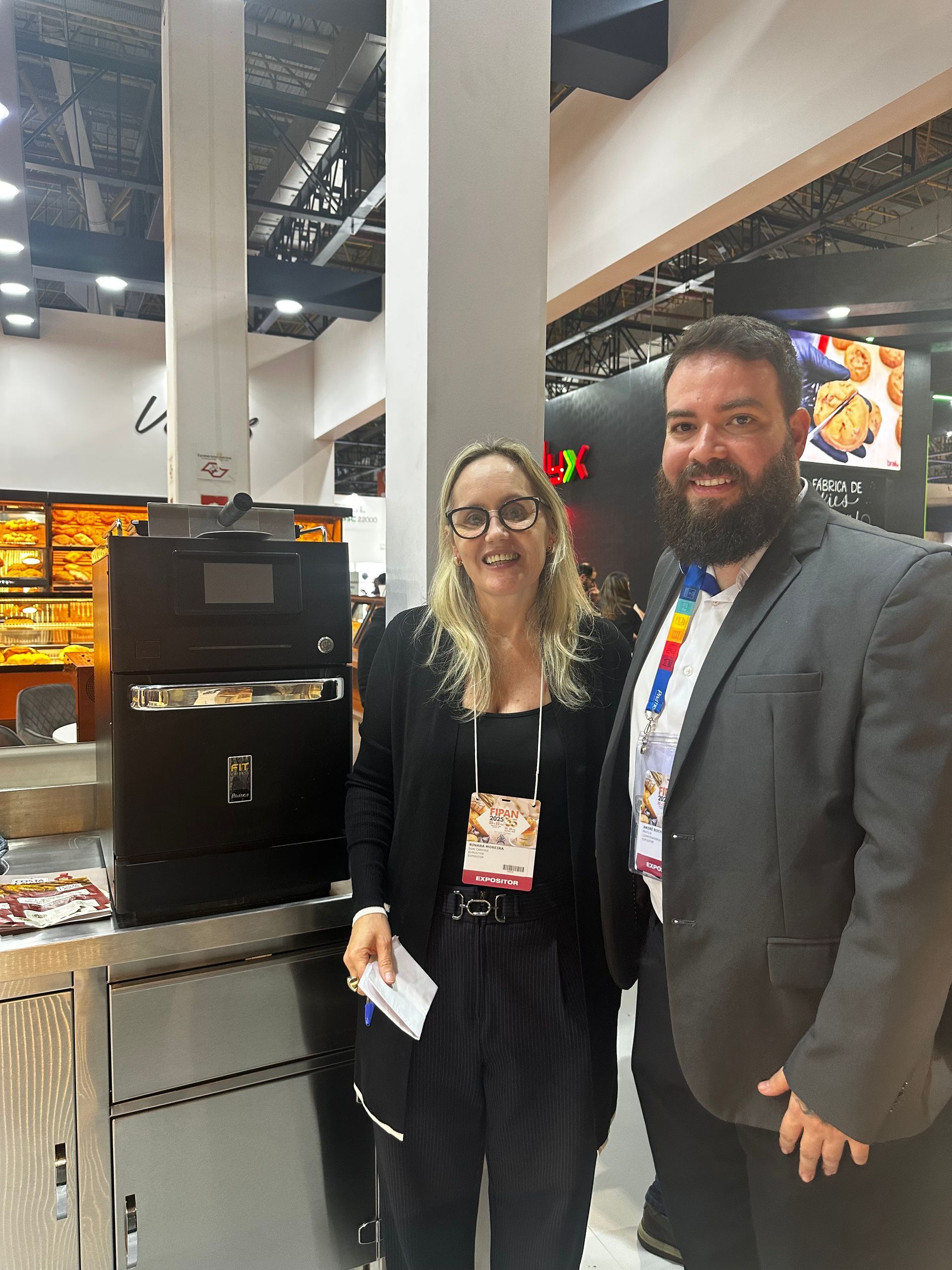 Um homem e uma mulher estão posando para uma foto em frente a uma máquina.
