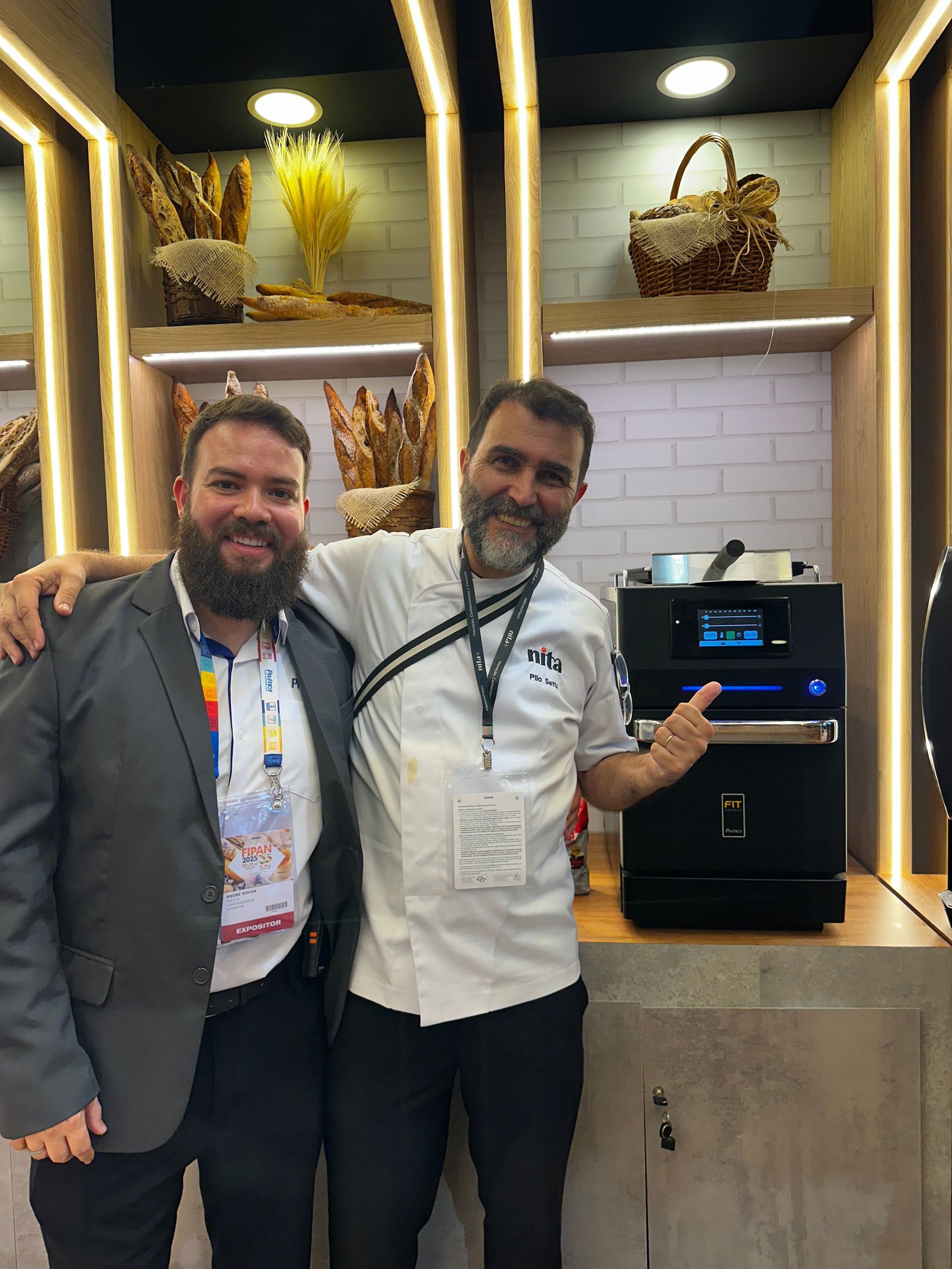 Dois homens estão posando para uma foto em frente a uma máquina.