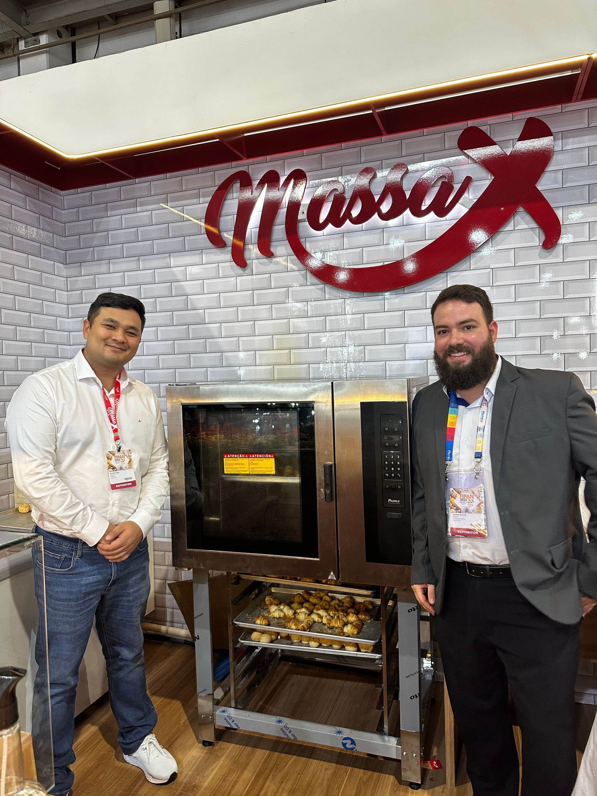 Dois homens estão parados um ao lado do outro em frente a um forno.