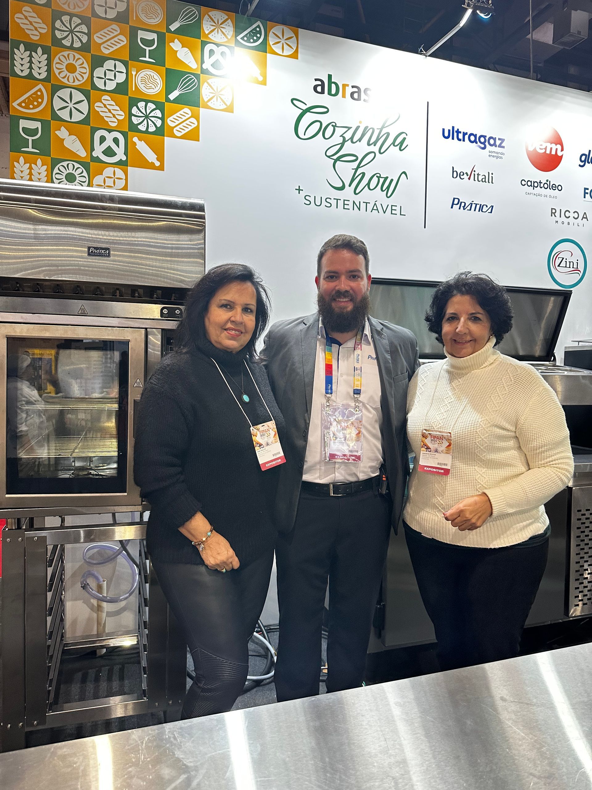 Um homem e duas mulheres estão posando para uma foto em uma cozinha.