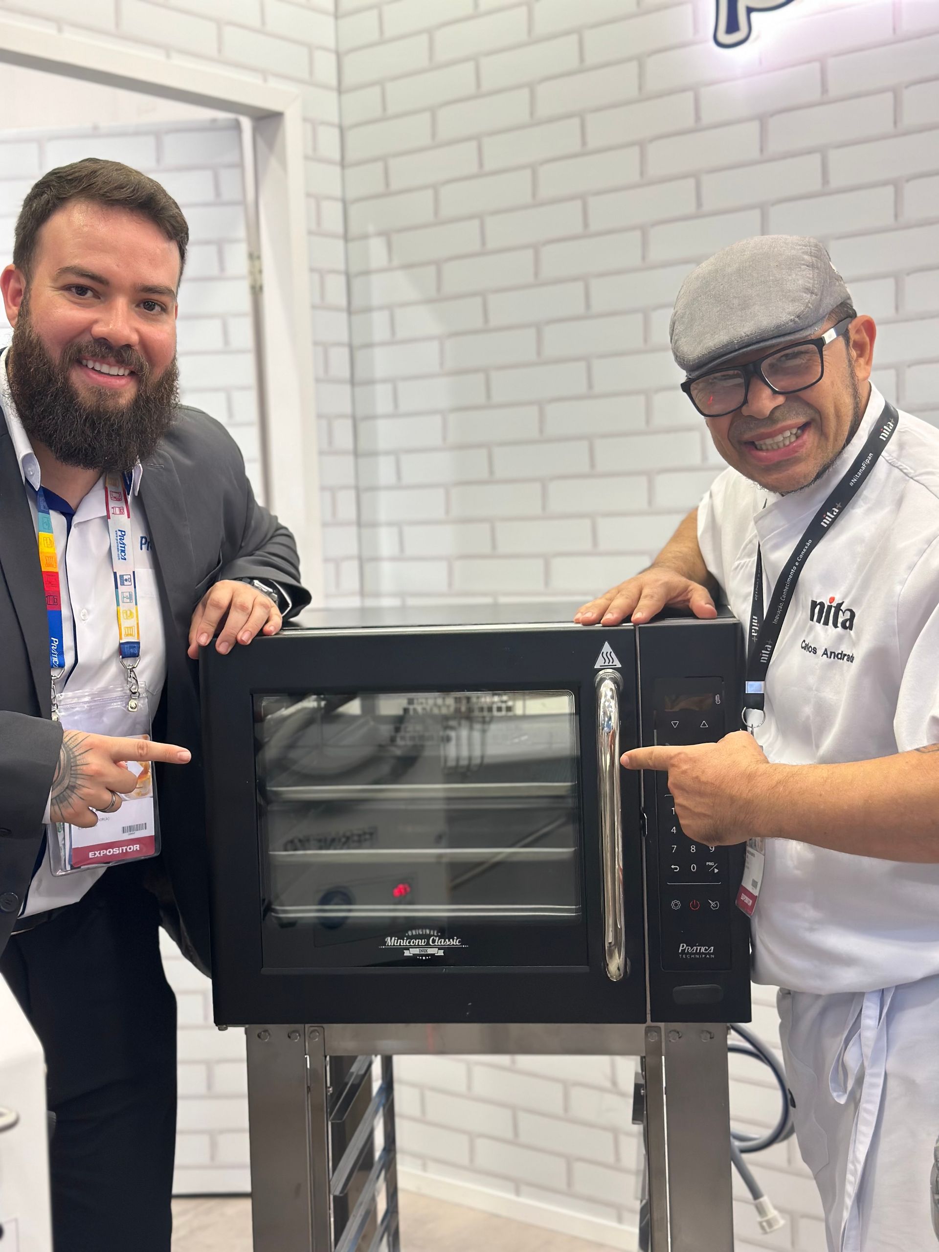 Dois homens estão parados ao lado de um forno preto.