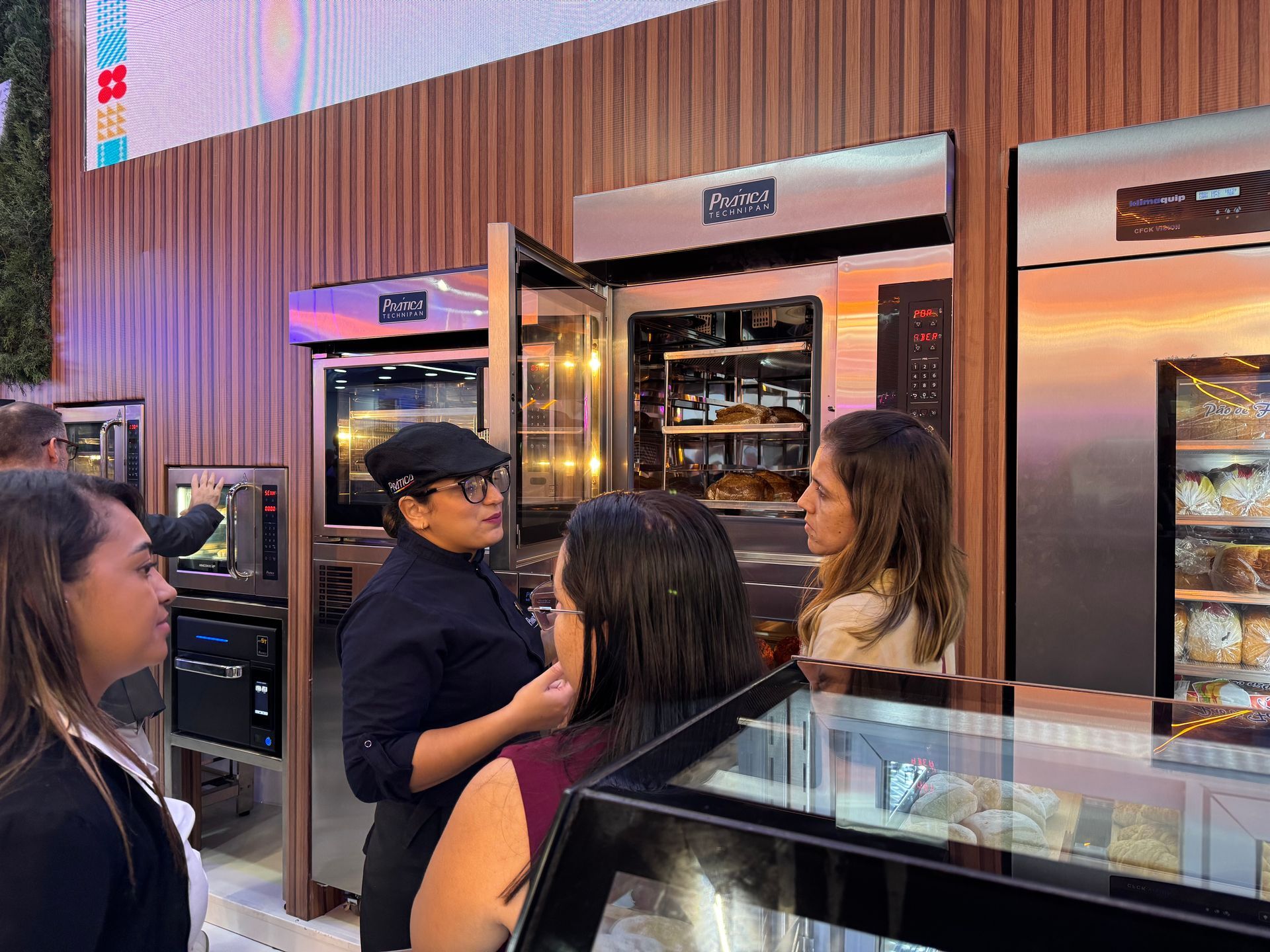 Um grupo de pessoas está em frente a uma padaria conversando entre si.