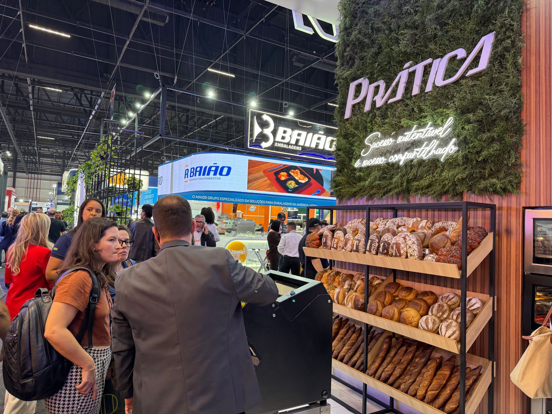 Um grupo de pessoas está em frente a uma exposição de pães.