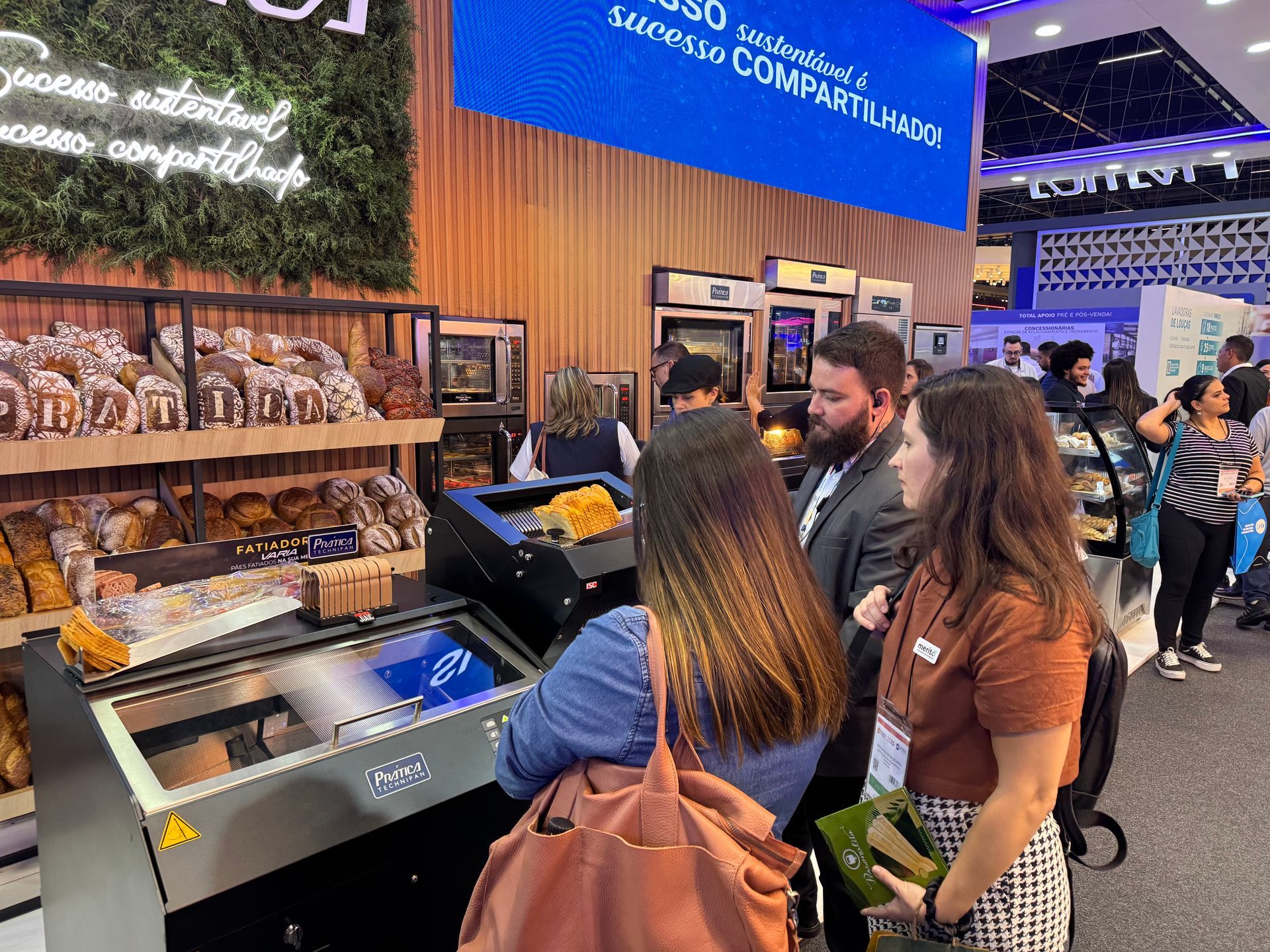 Um grupo de pessoas está em volta de uma vitrine em uma loja.