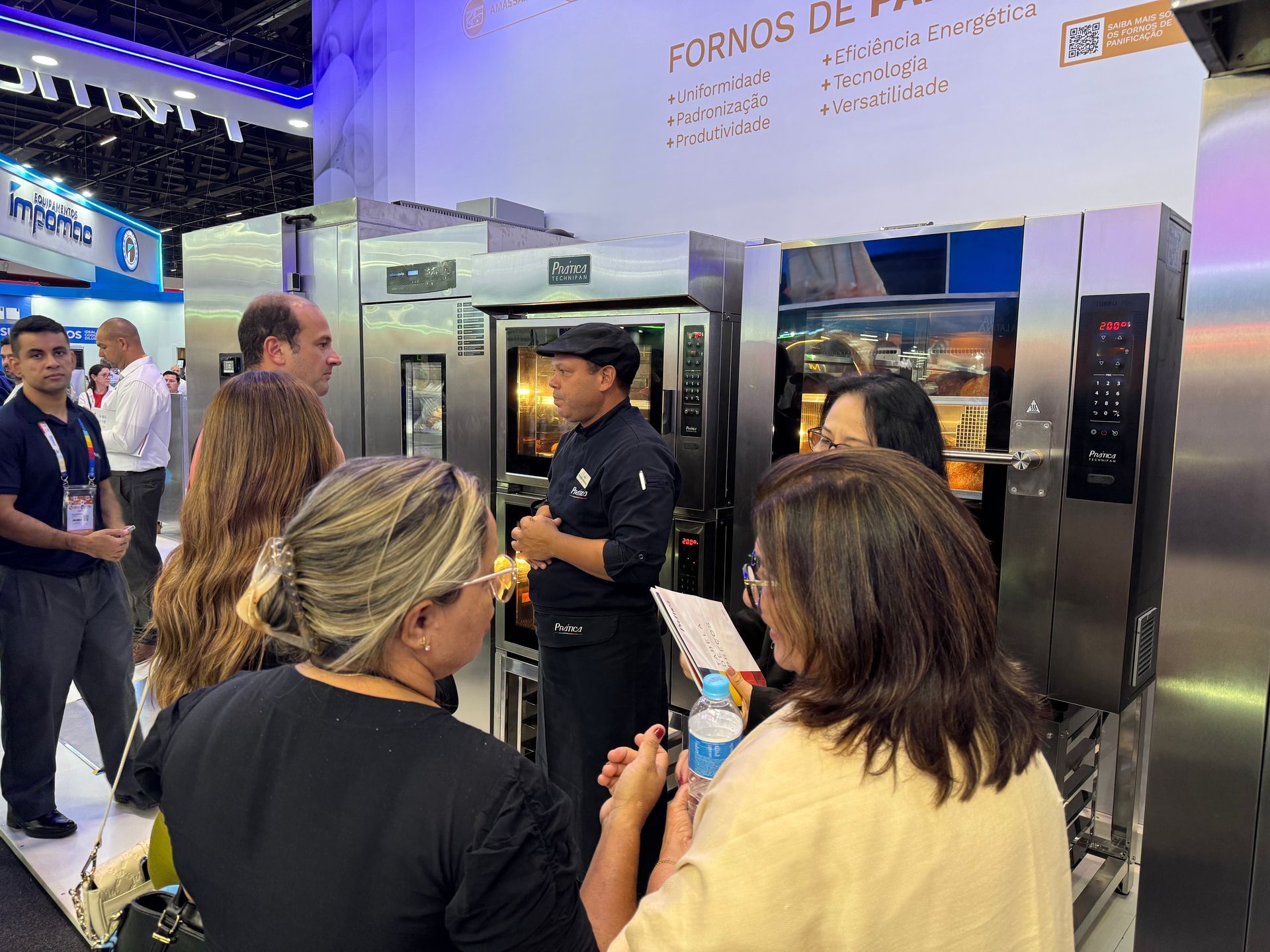 Um homem está conversando com um grupo de pessoas em uma padaria.