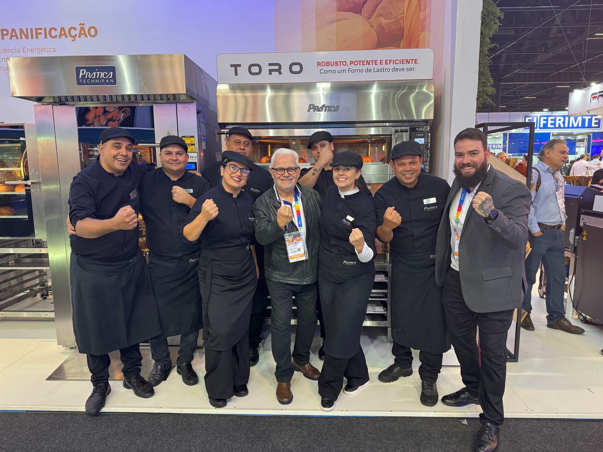 Um grupo de pessoas está posando para uma foto em frente a um forno toro.