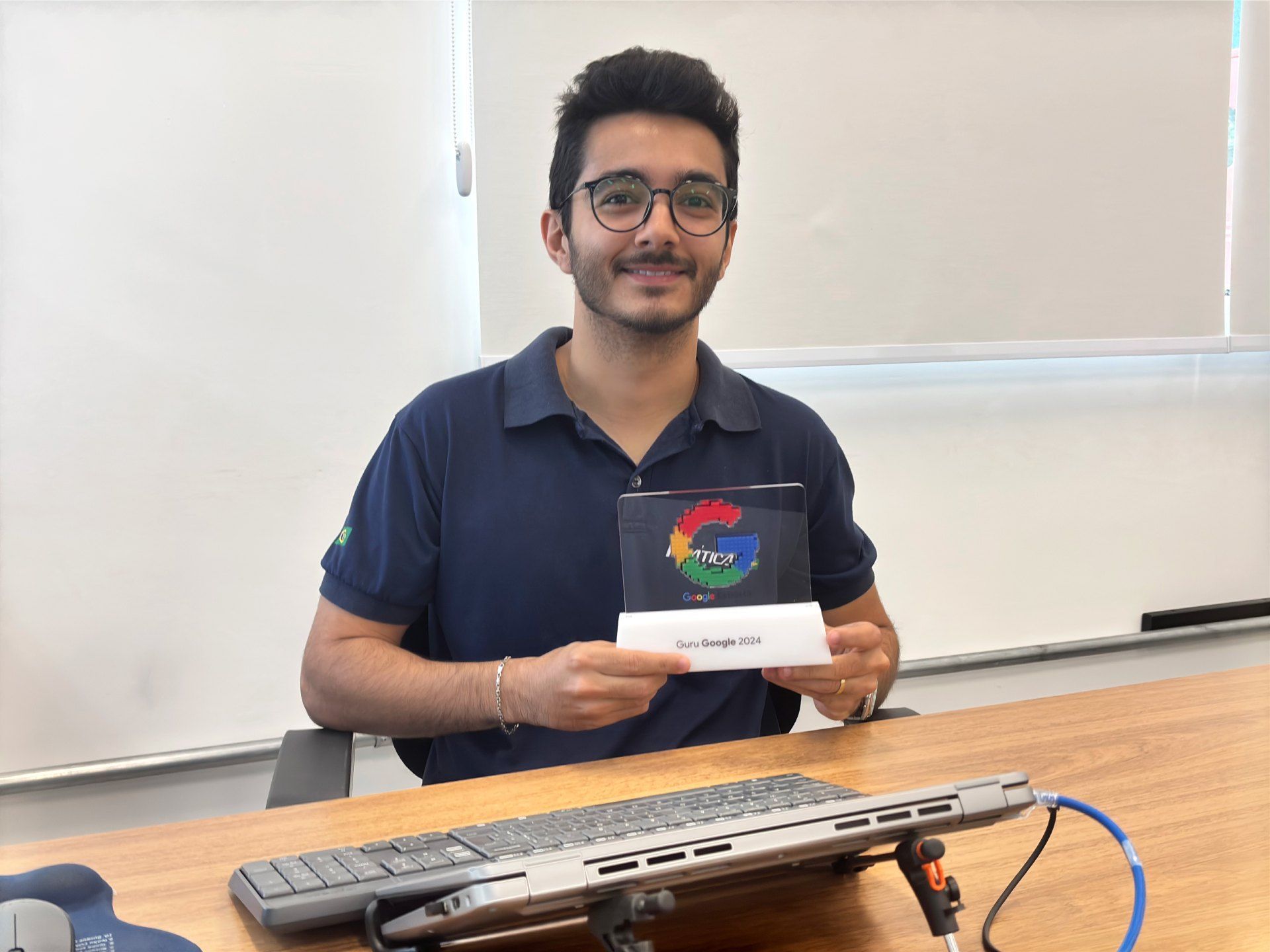 Um homem está sentado em uma mesa segurando um cartão do Google.