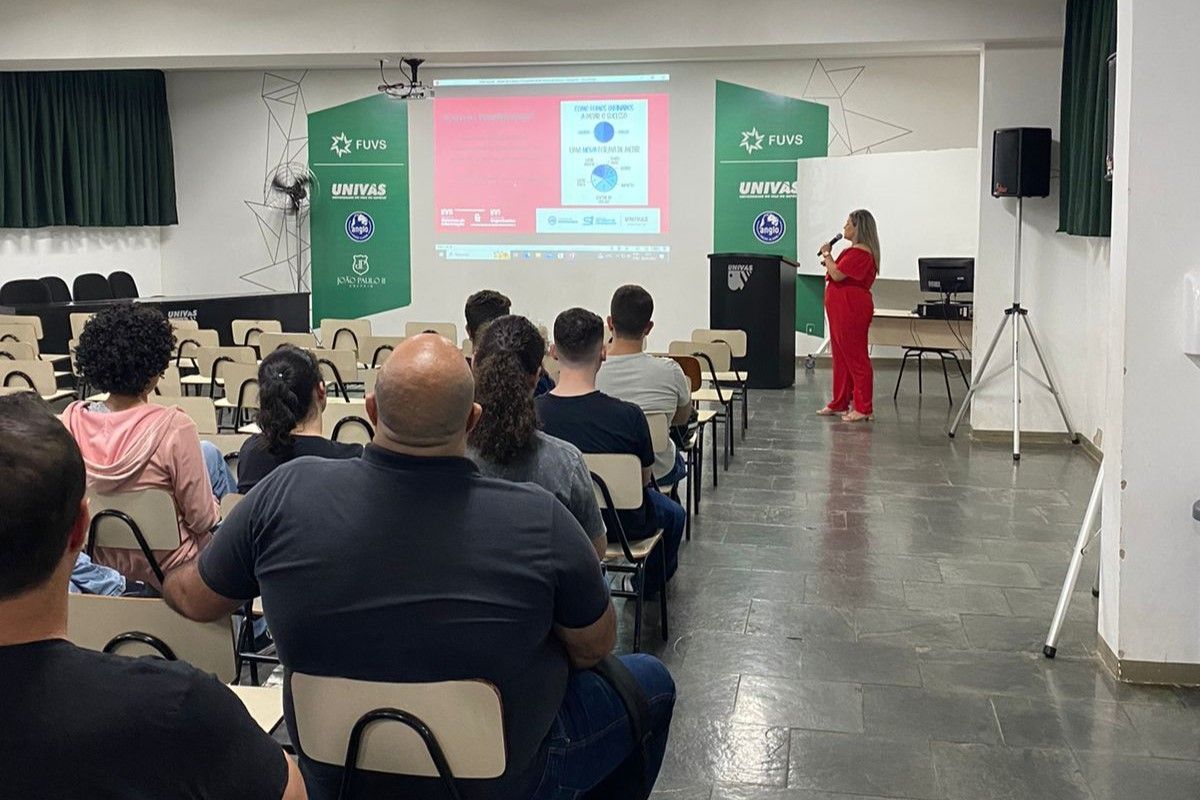 Uma mulher está fazendo uma apresentação para um grupo de pessoas em uma sala de aula.