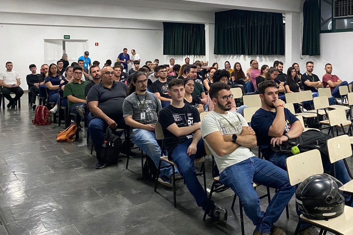 Um grande grupo de pessoas está sentado em cadeiras em uma sala.