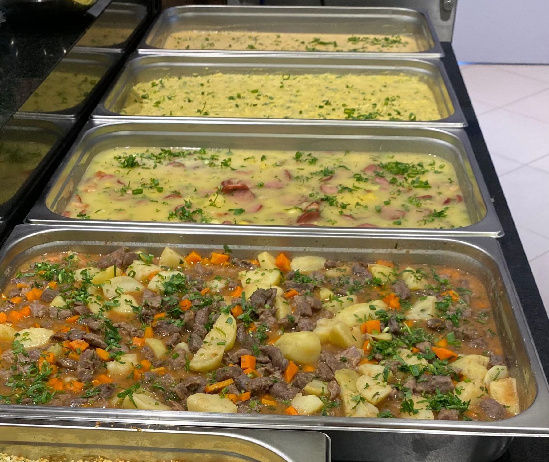 Várias bandejas de comida estão alinhadas sobre uma mesa