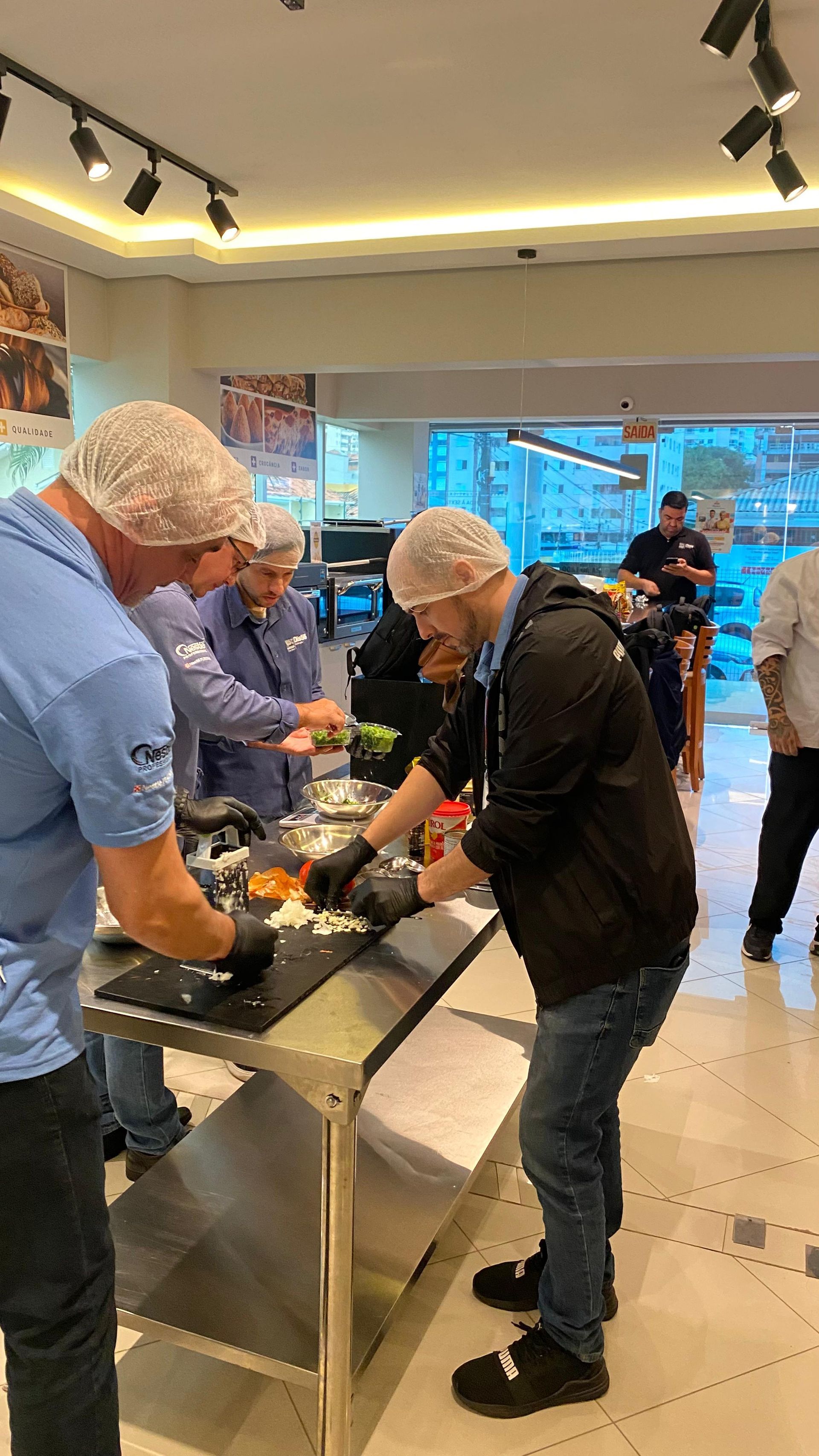 Um grupo de homens está em volta de uma mesa preparando comida.