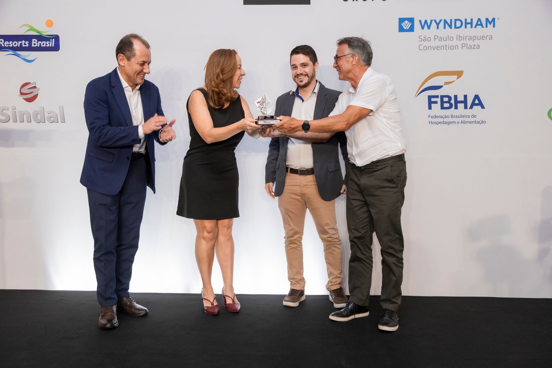 Um grupo de pessoas está de pé, uma ao lado da outra, em um palco.