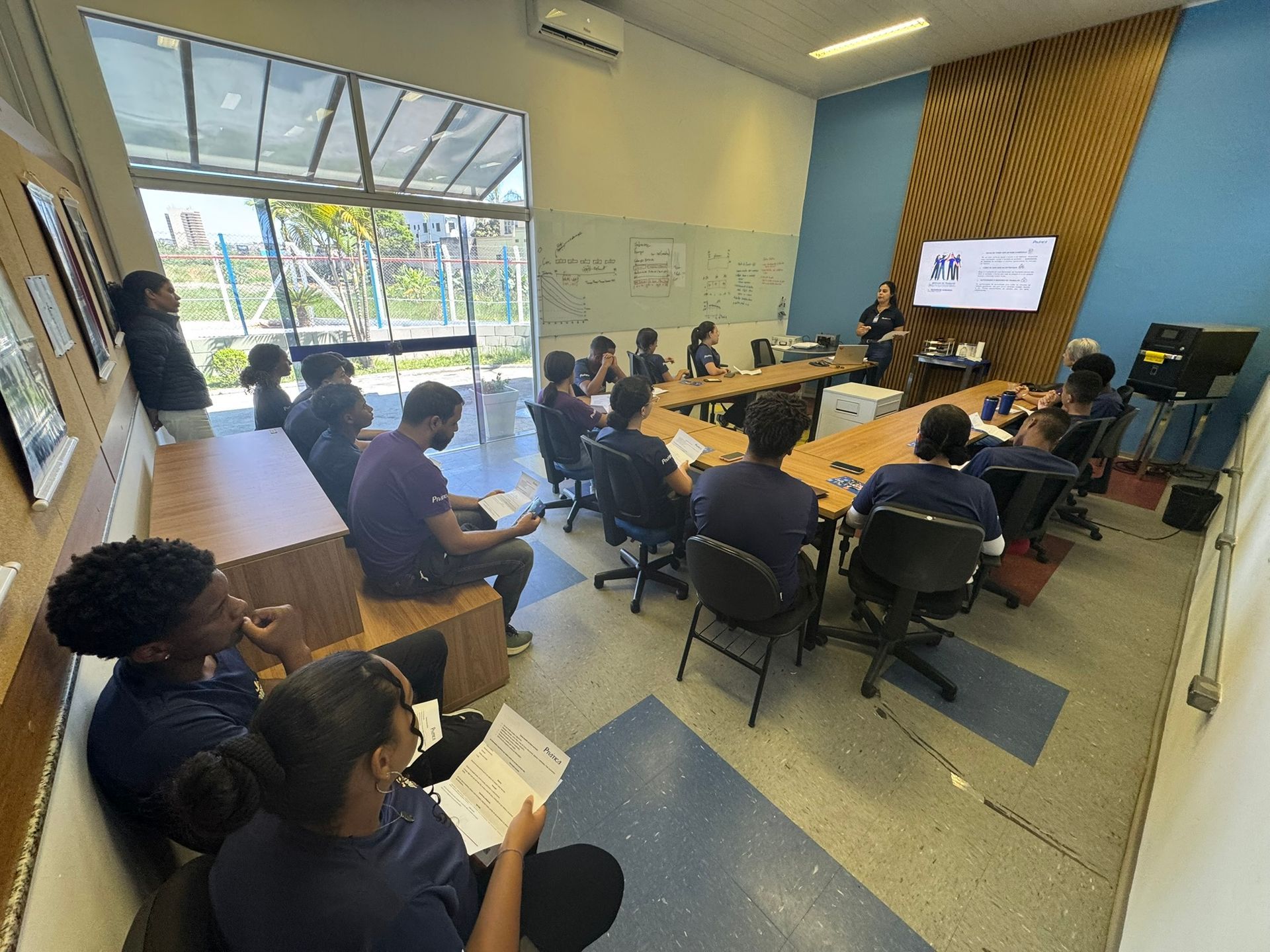 Um grupo de estudantes assiste a uma apresentação em uma sala de aula moderna.