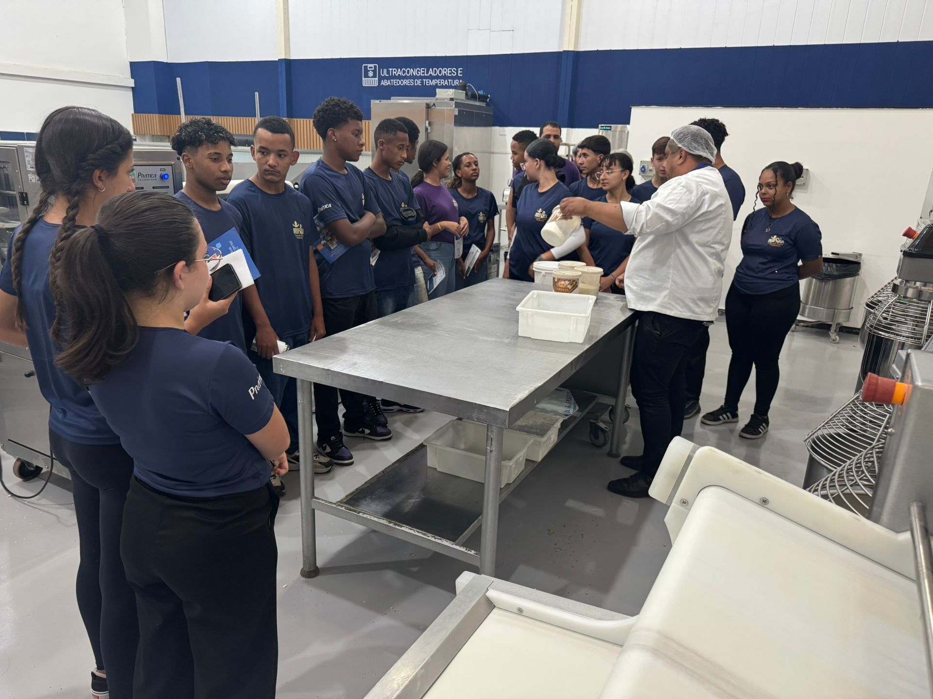 Um grupo de estudantes assiste a uma demonstração de um chef na cozinha.