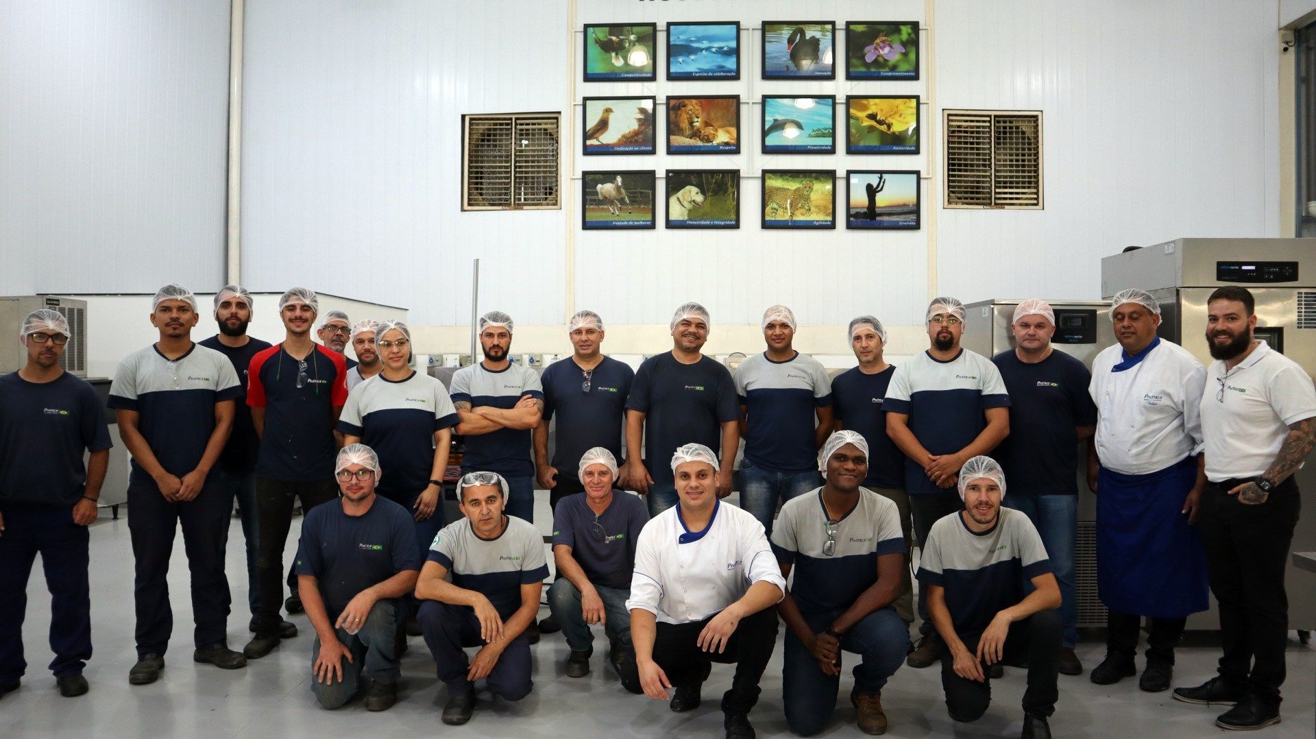 Um grupo de homens está posando para uma foto em uma fábrica.