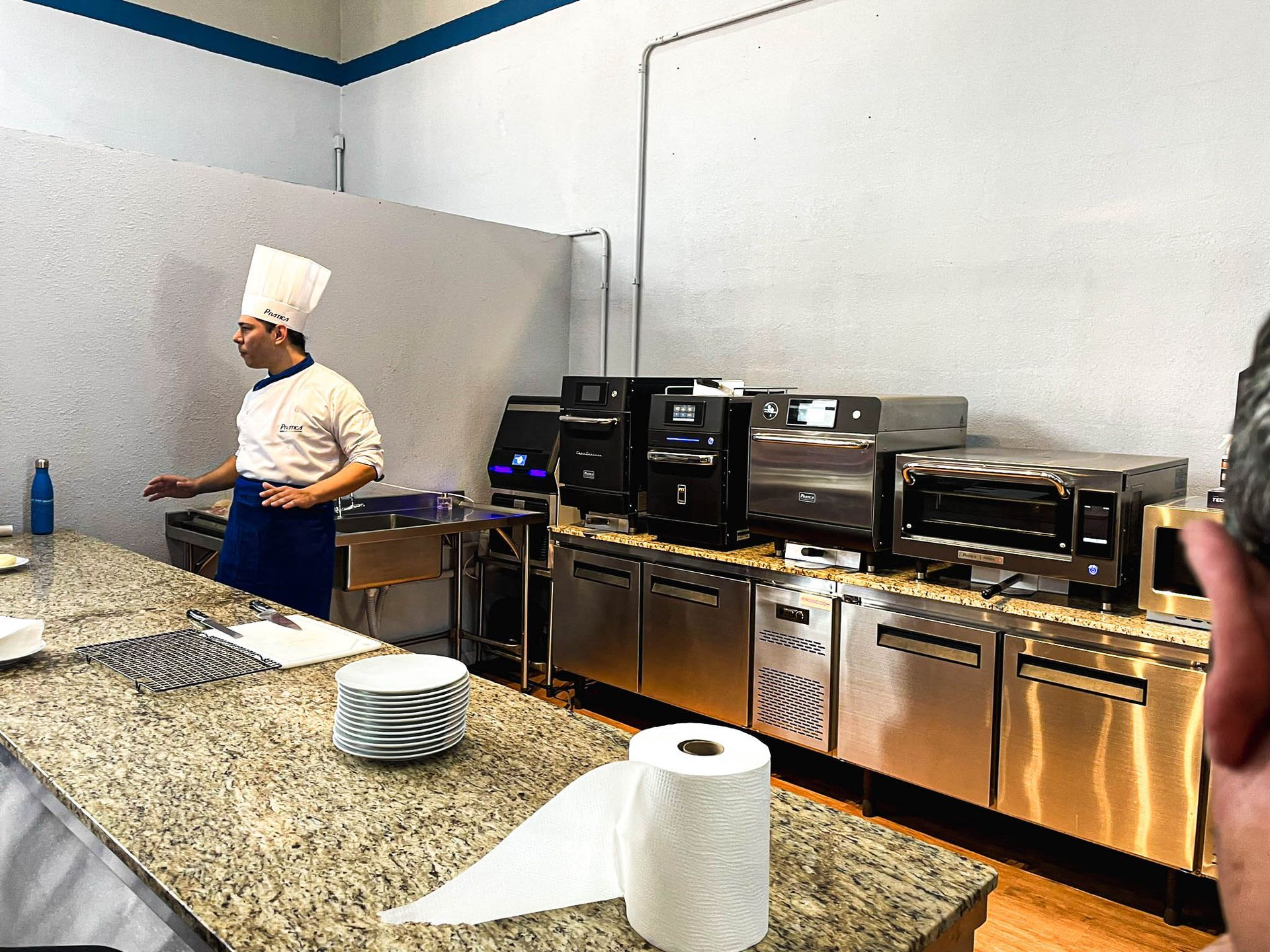 Um homem com chapéu de chef está parado em uma cozinha