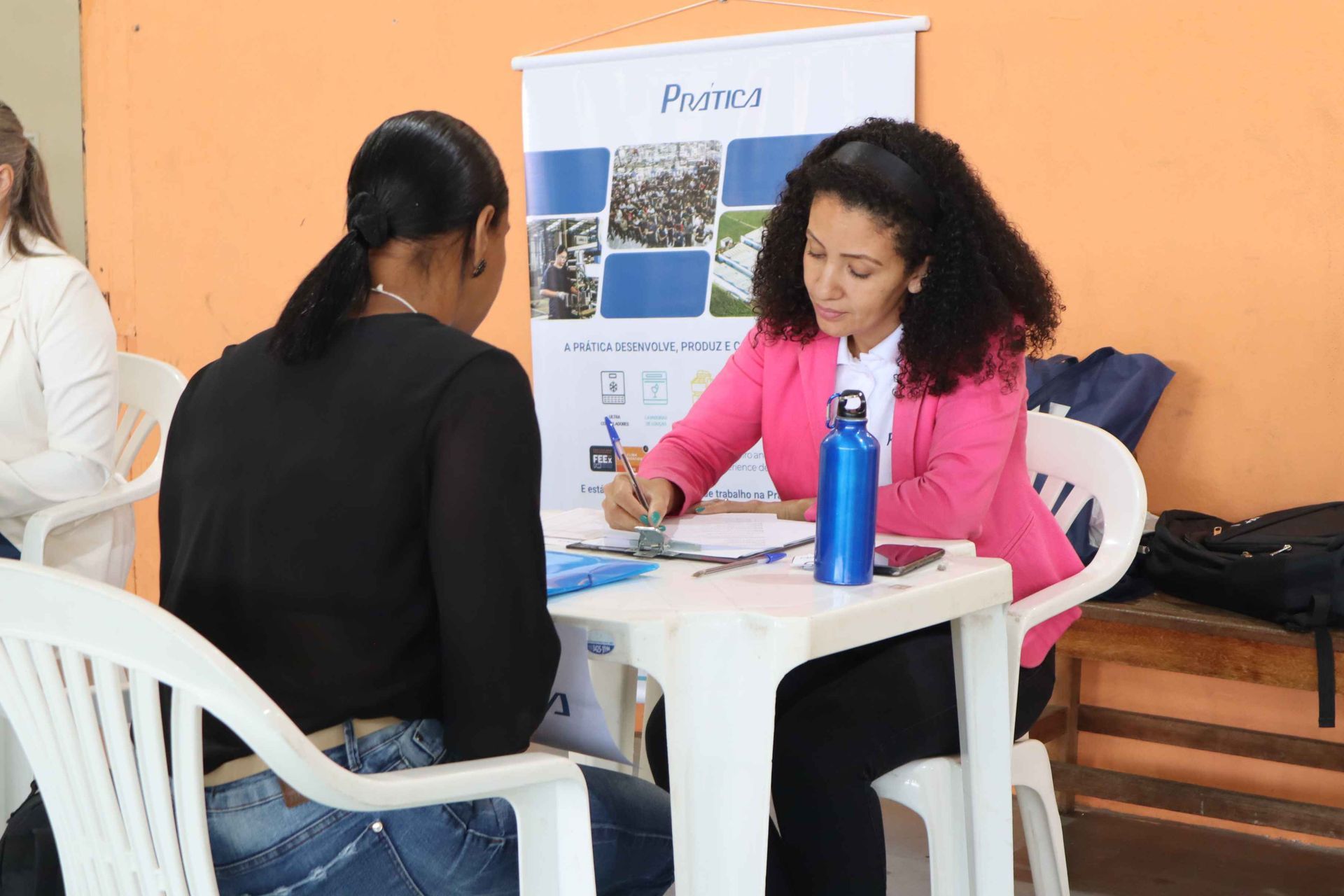 Duas mulheres estão sentadas à mesa conversando uma com a outra.