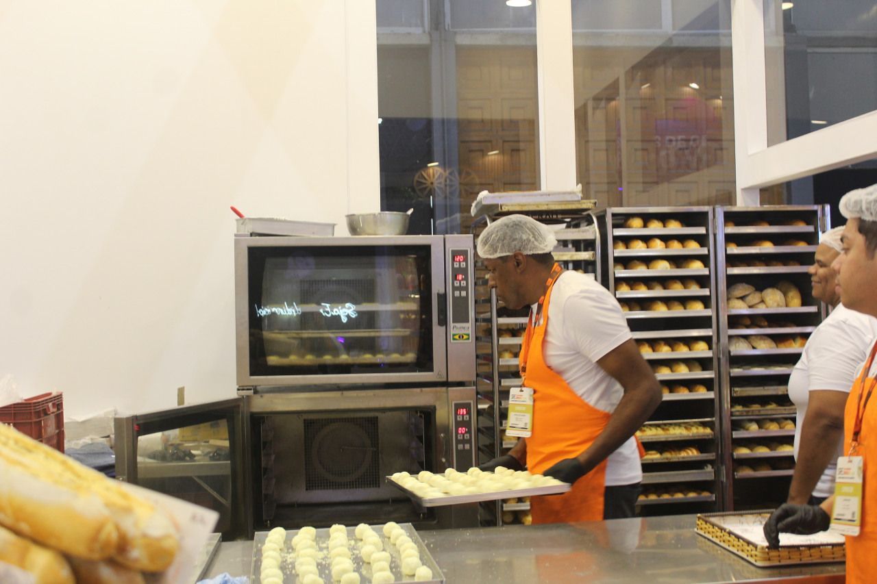 Um homem está segurando uma bandeja de pão em uma padaria
