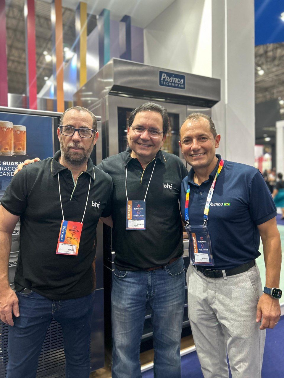 Três homens estão posando para uma foto em frente a uma máquina.