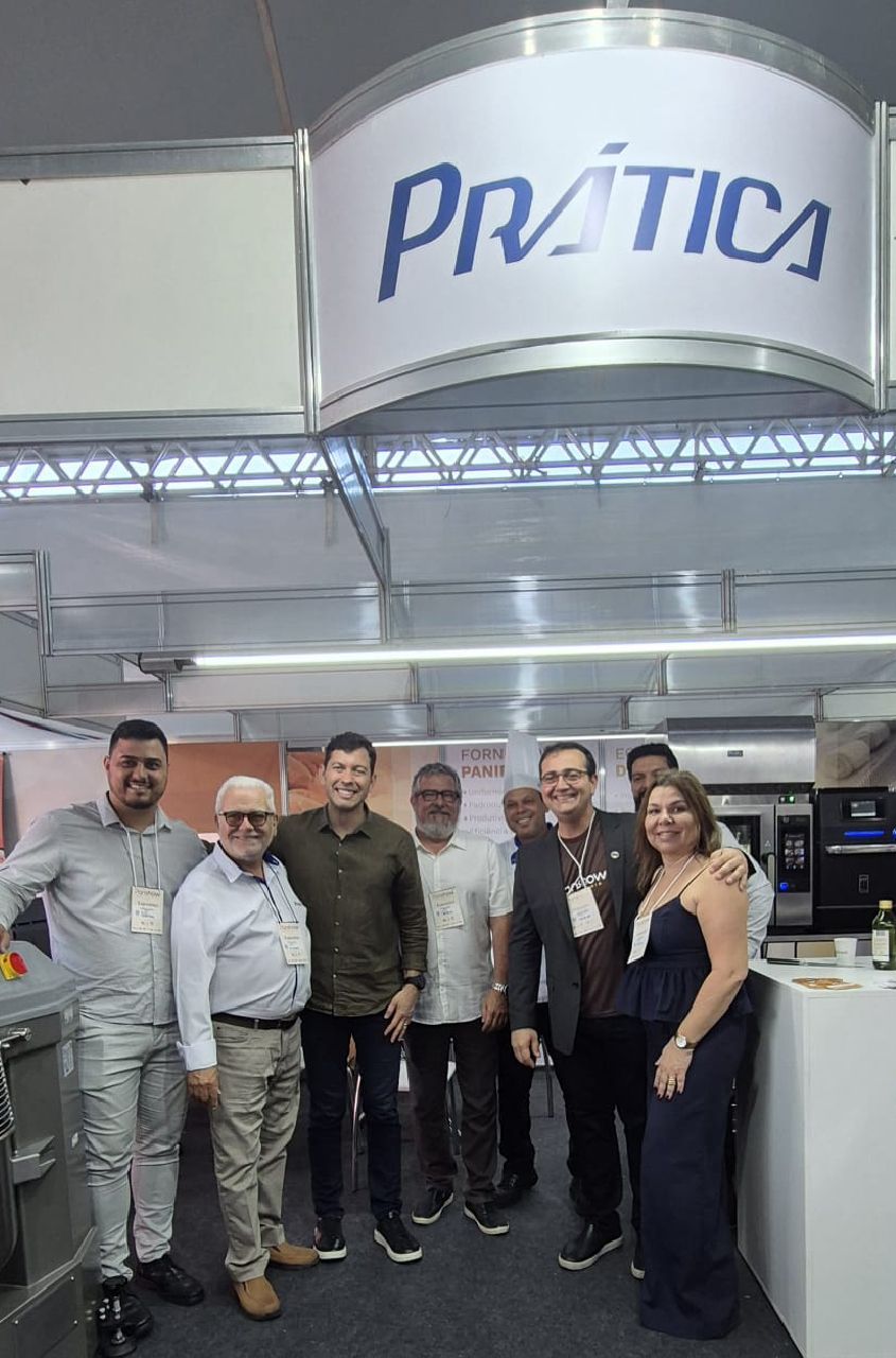 Um grupo de pessoas está posando para uma foto em frente a uma placa de prática.