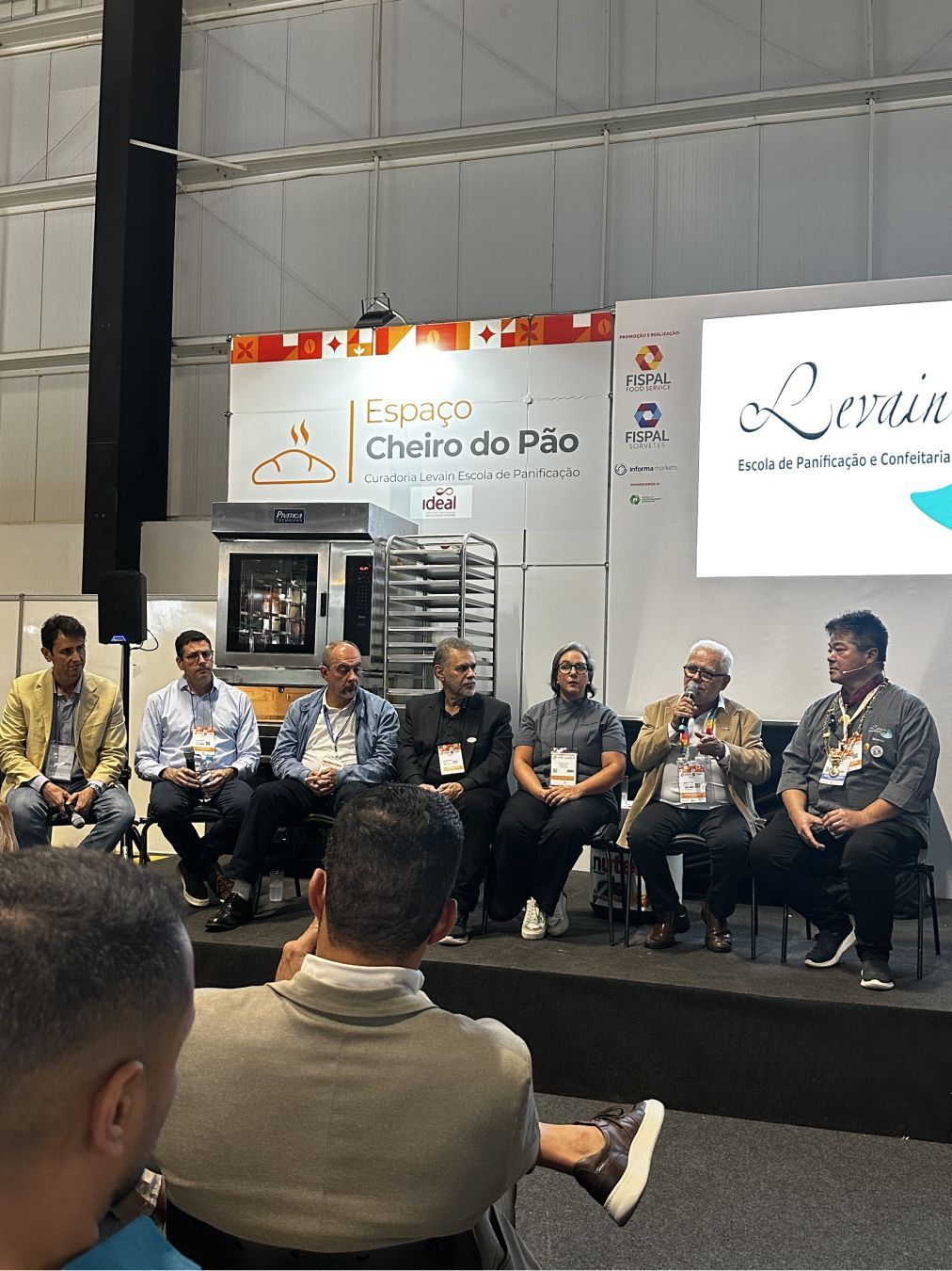 Um grupo de homens está sentado em cadeiras em frente a um palco.