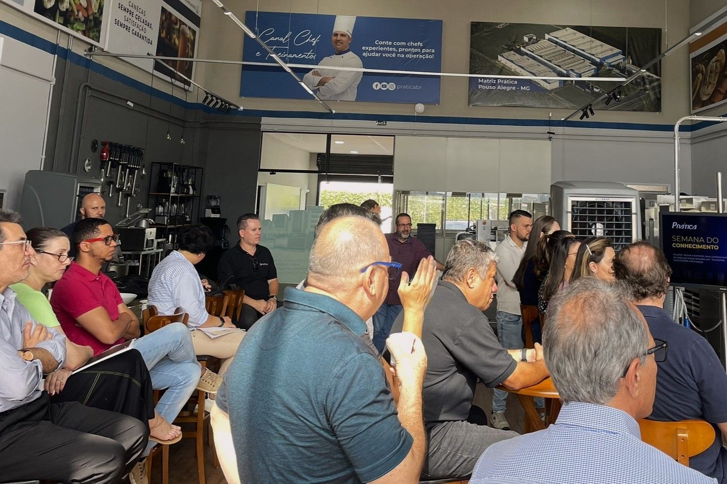Um grupo de pessoas está sentado em mesas em uma sala.