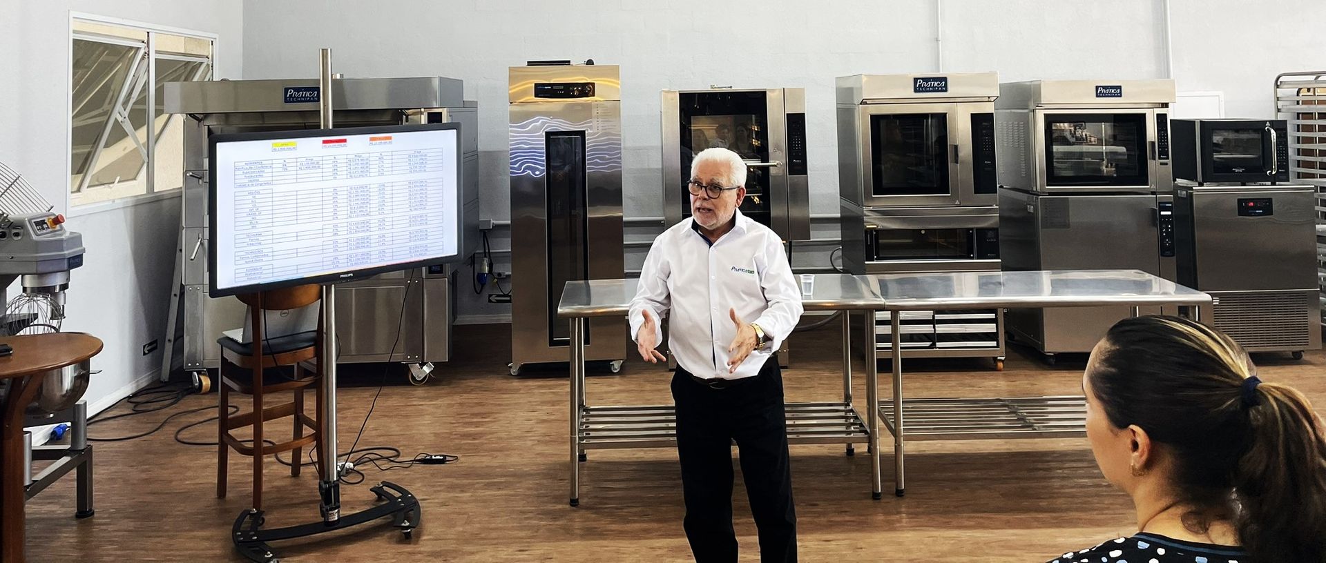 Um homem está fazendo uma apresentação para uma mulher na cozinha.