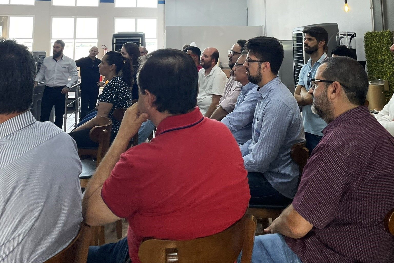 Um grupo de pessoas está sentado em cadeiras assistindo a uma apresentação.