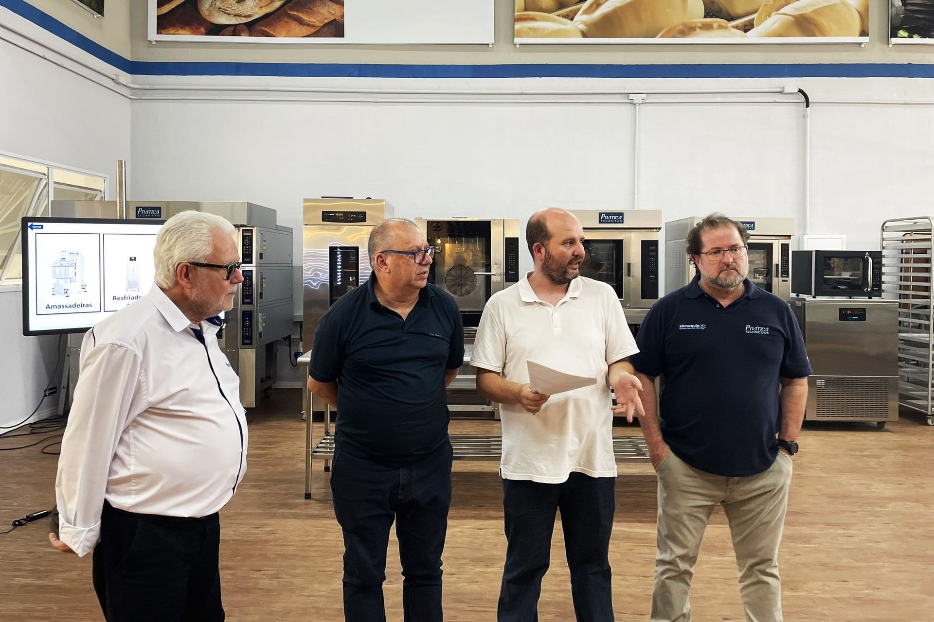 Um grupo de homens está em uma padaria conversando entre si.