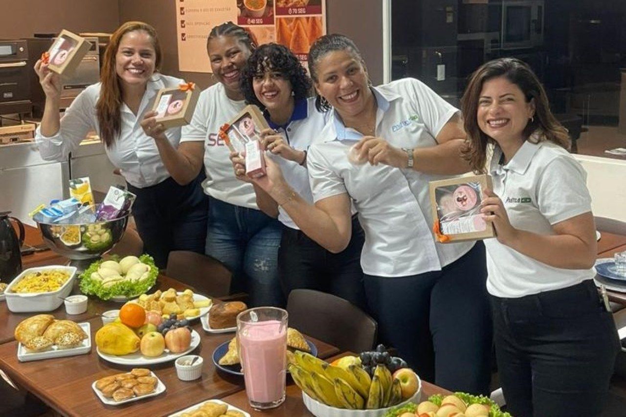 Um grupo de mulheres está posando para uma foto em frente a uma mesa cheia de comida.