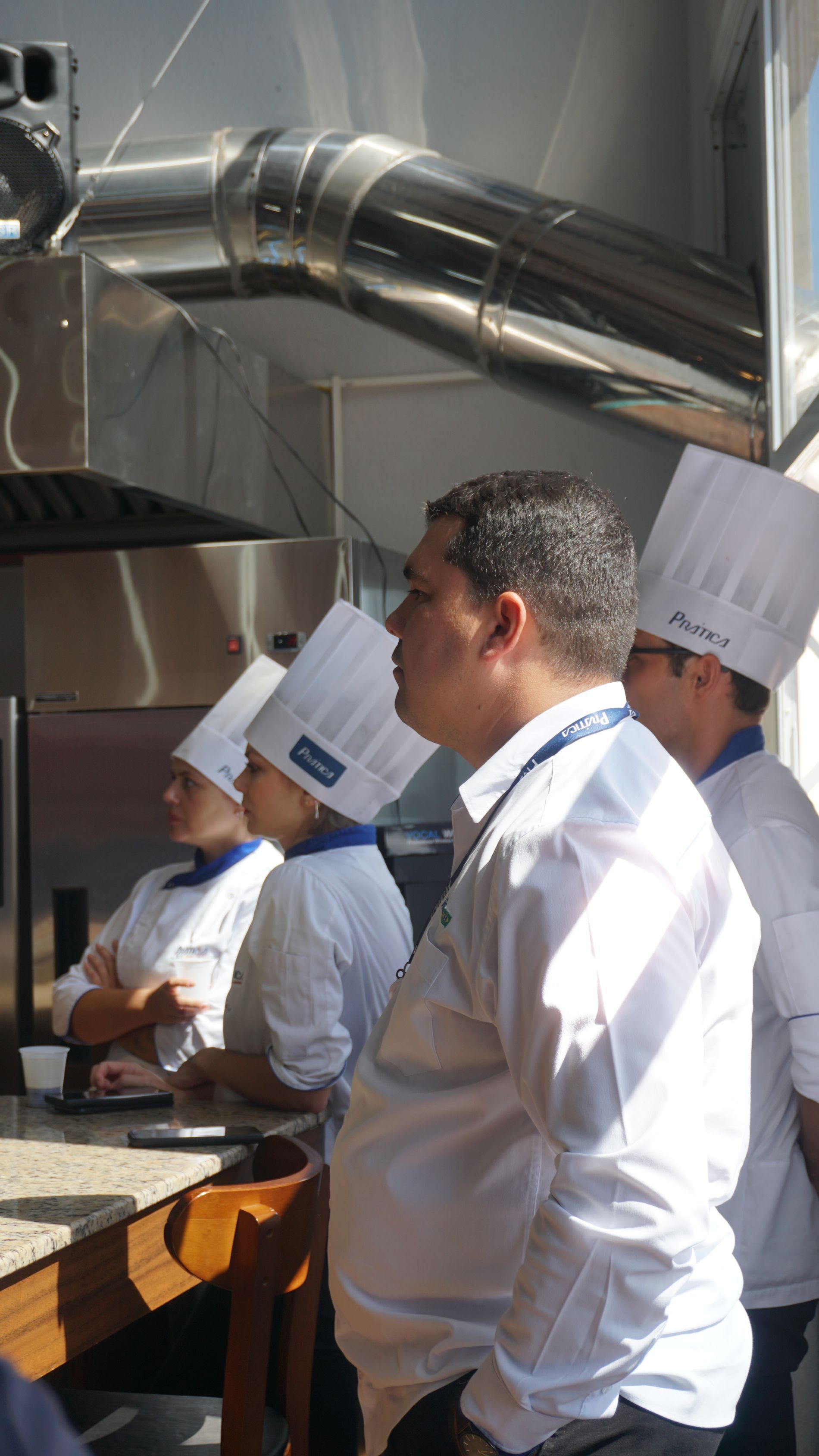 Um grupo de chefs está em uma cozinha usando chapéus de chef