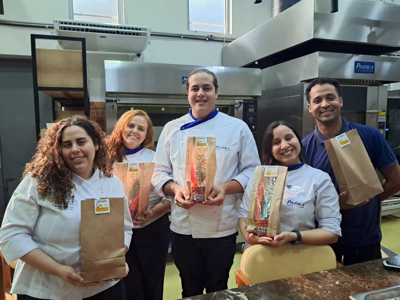 Um grupo de pessoas está em uma cozinha segurando sacos de comida.