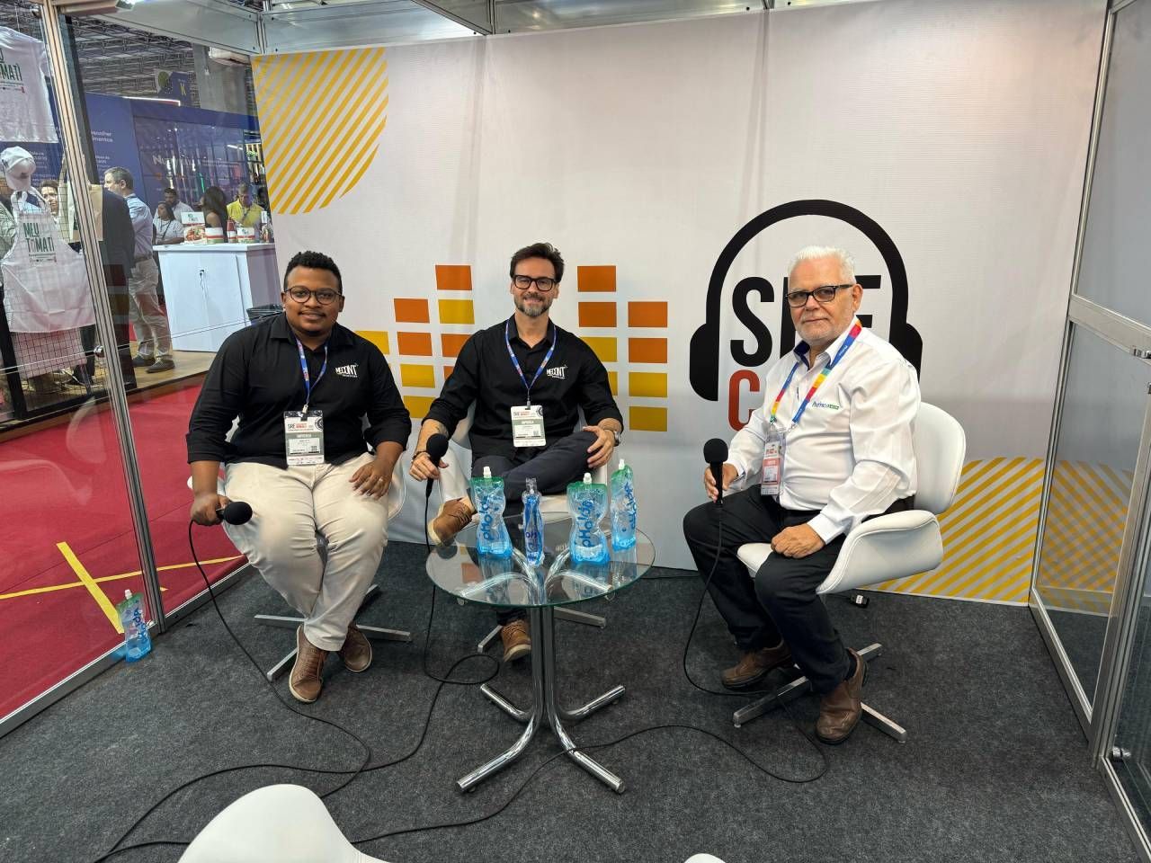 Três homens estão sentados à mesa em uma sala.
