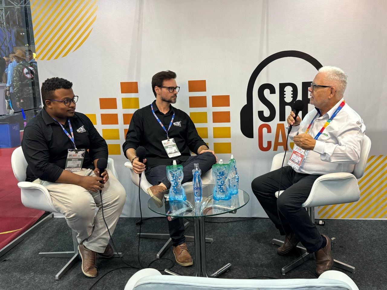 Três homens estão sentados à mesa conversando entre si