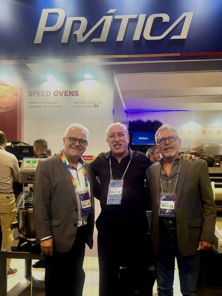 Três homens estão posando para uma foto em frente a uma placa de prática