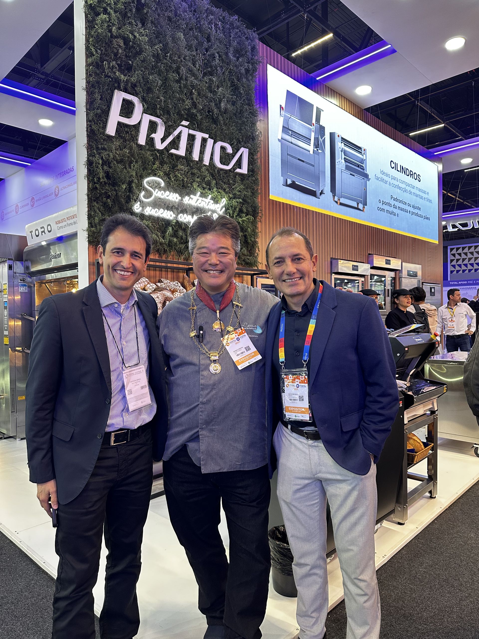 Três homens estão posando para uma foto em uma convenção.