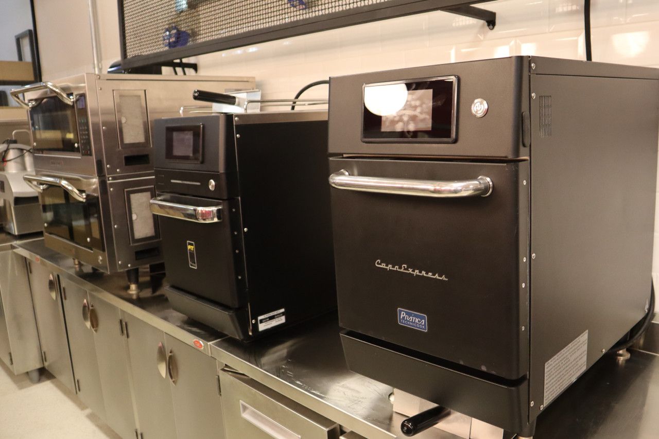 Dois fornos pretos estão sobre um balcão de aço inoxidável.