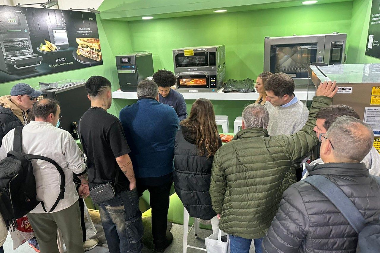 Um grupo de pessoas está em uma sala olhando para um forno de micro-ondas.