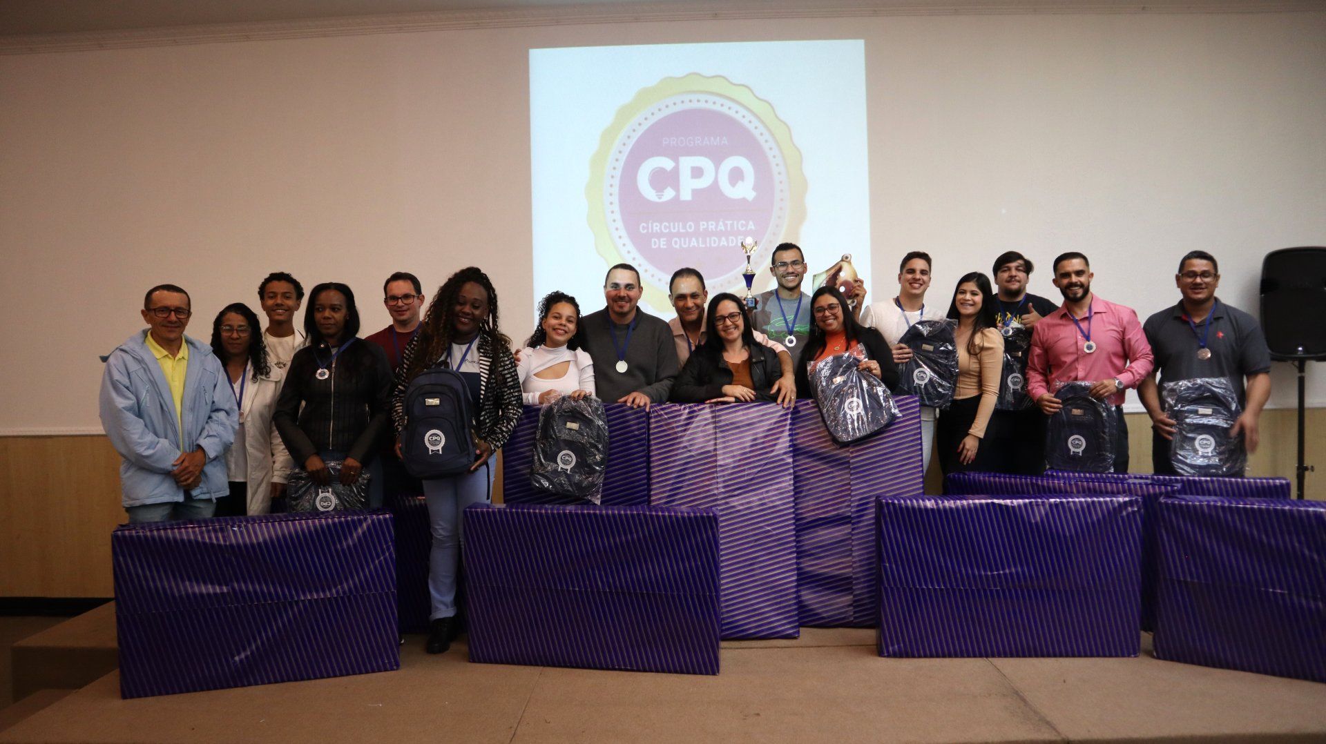 Um grupo de pessoas está posando para uma foto em frente a uma tela de projetor.