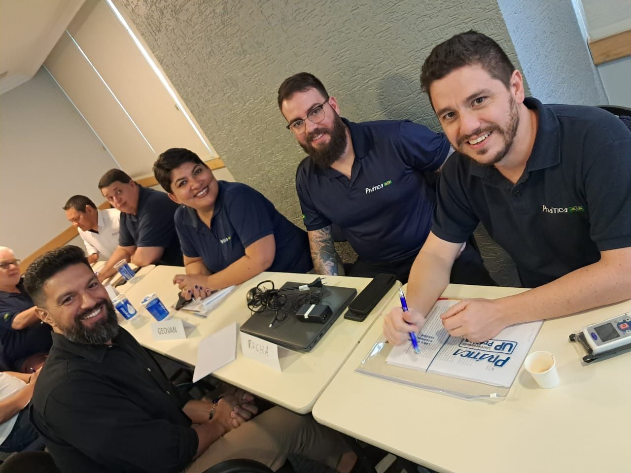 Um grupo de pessoas está sentado em mesas em uma sala.