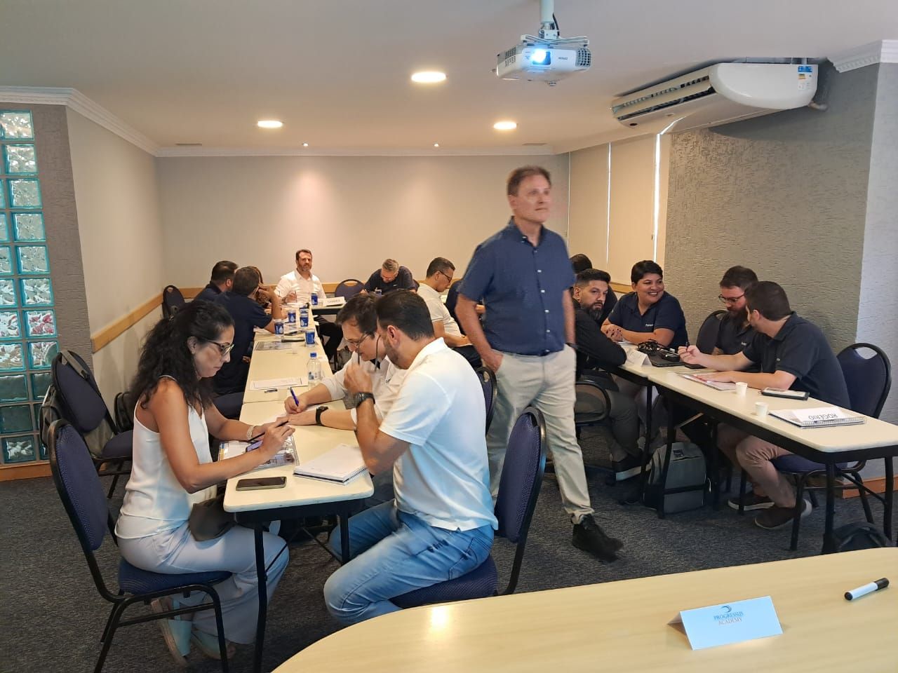 Um grupo de pessoas está sentado em mesas em uma sala de conferências.