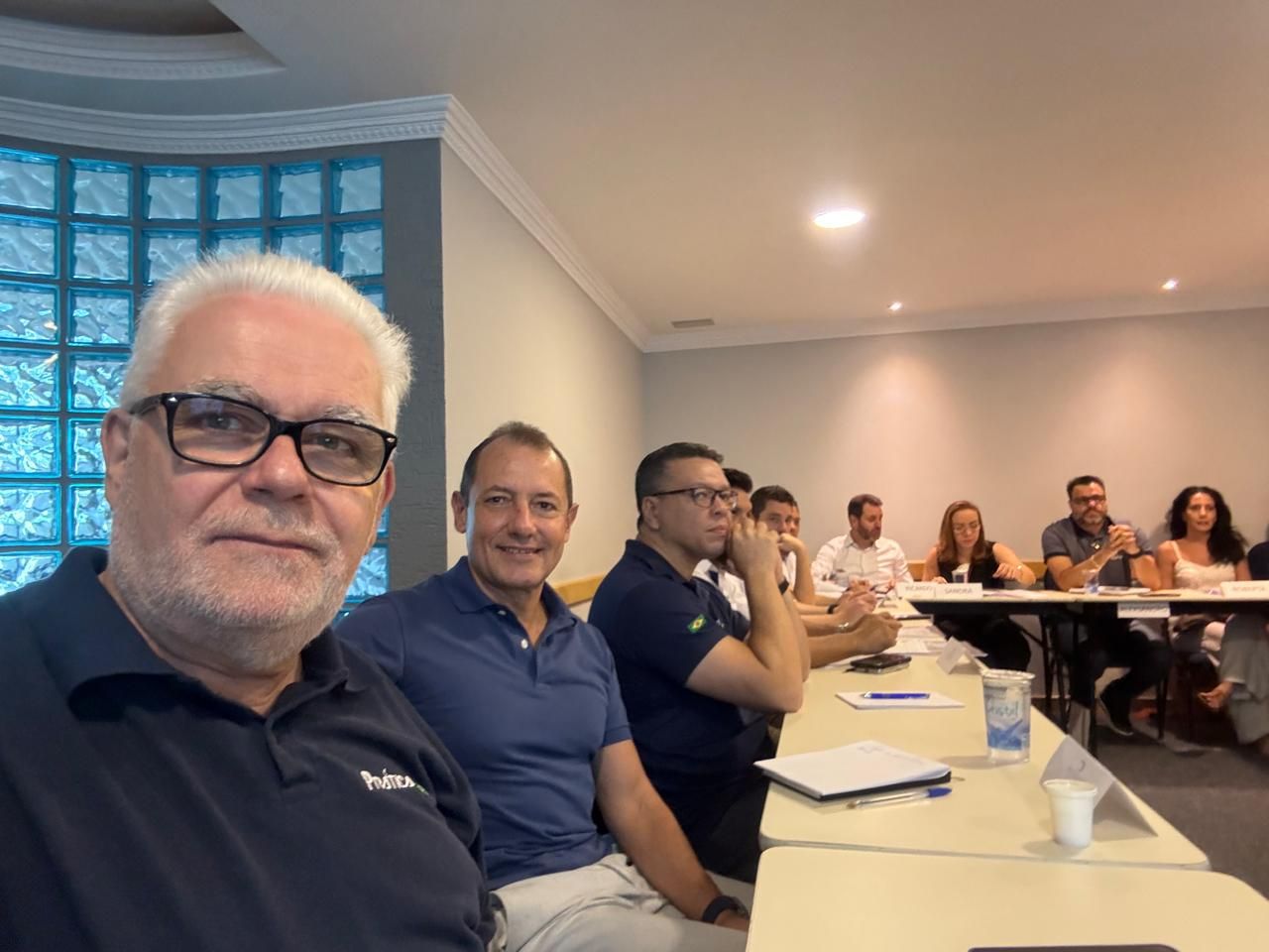 Um grupo de pessoas está sentado em mesas em uma sala.