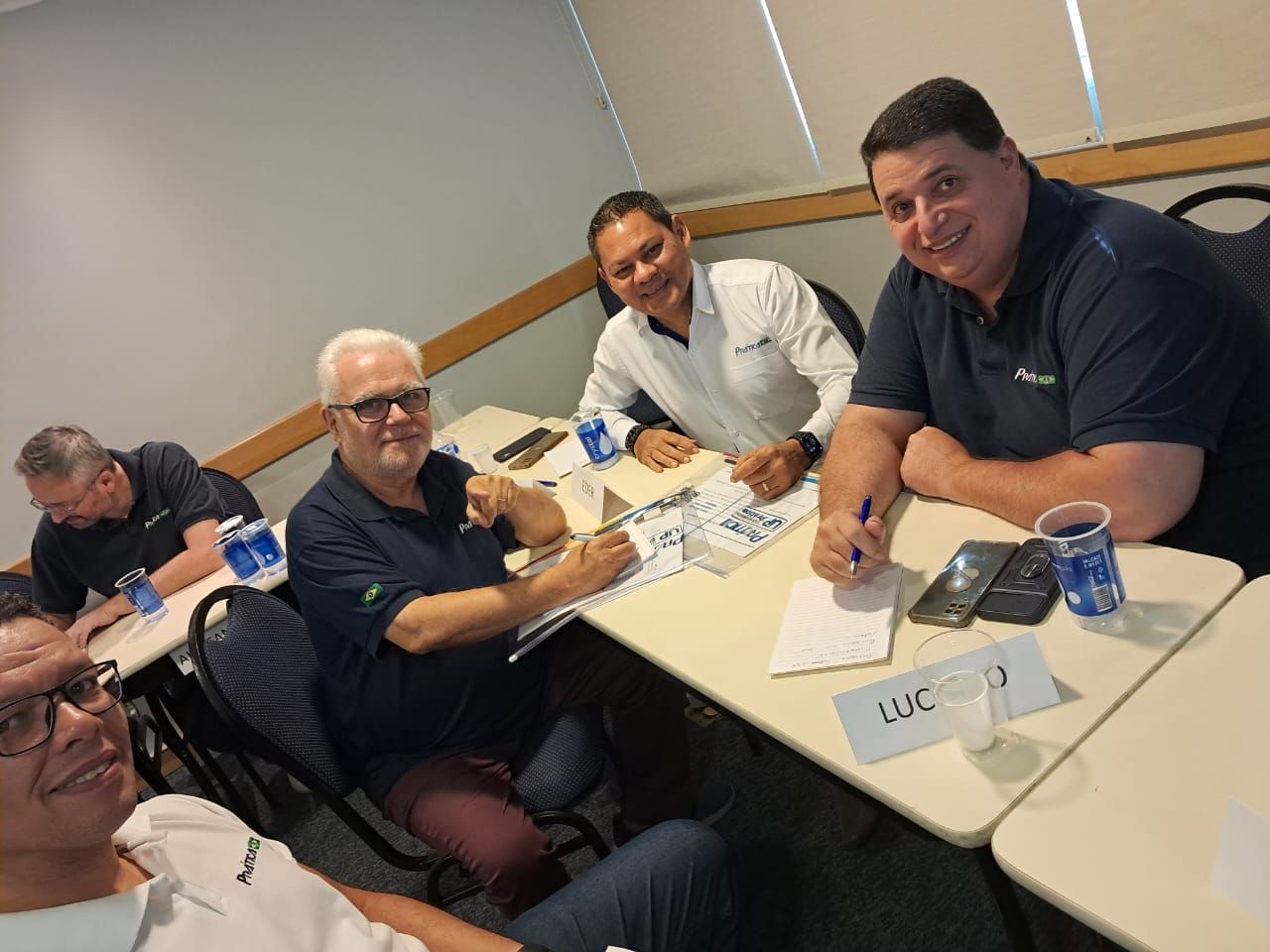 Um grupo de homens está sentado ao redor de uma mesa em uma sala.