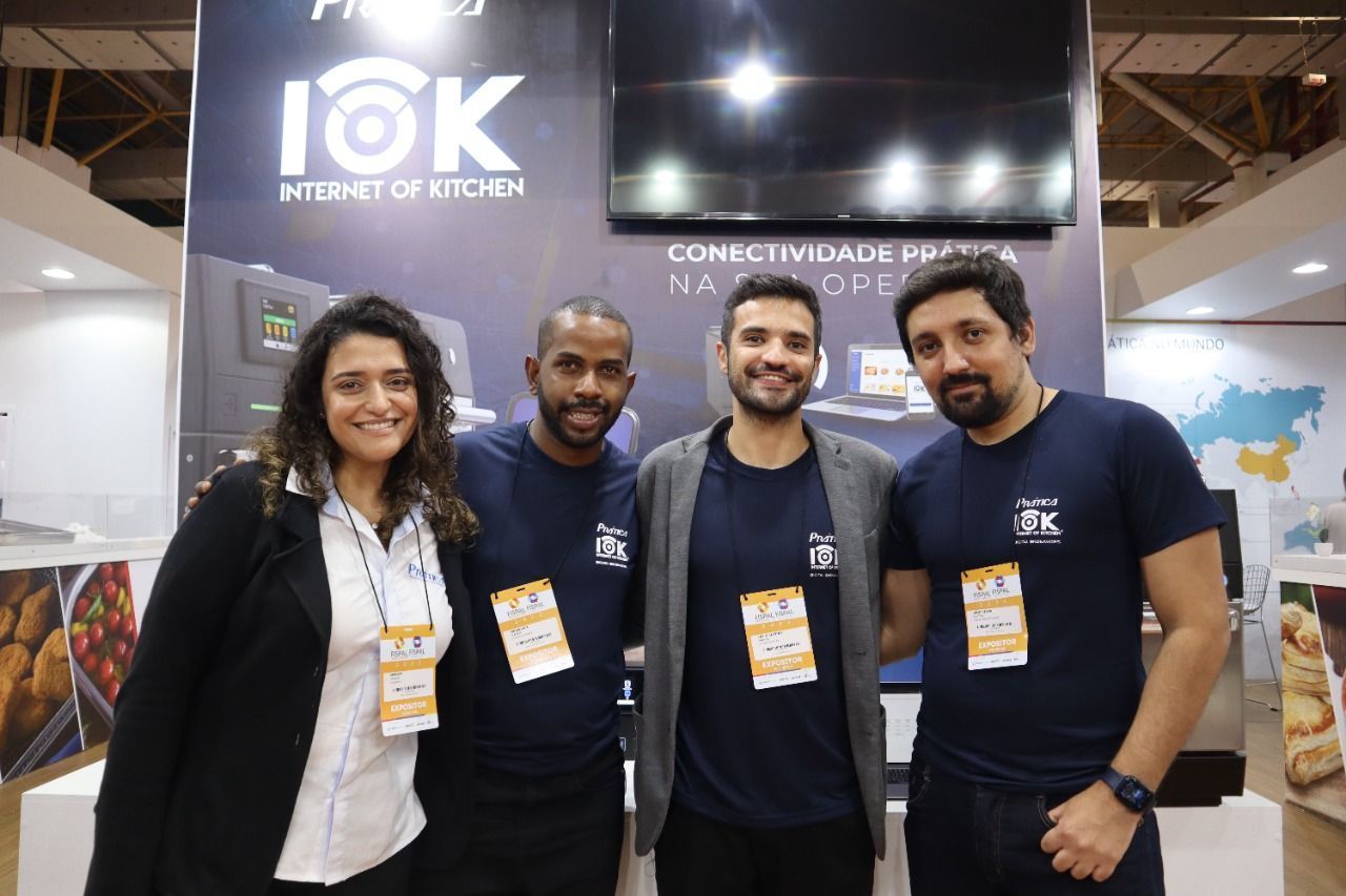 Um grupo de pessoas está posando para uma foto em frente a uma placa que diz