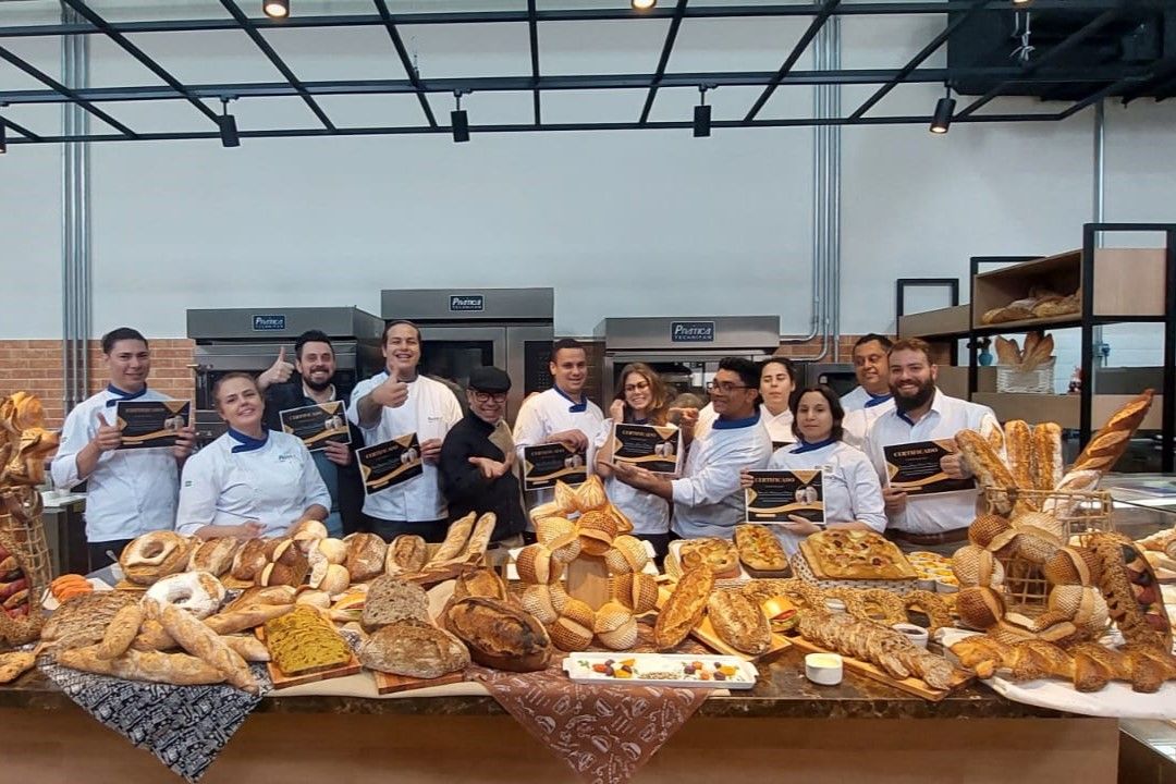 Um grupo de pessoas está posando para uma foto em frente a uma mesa cheia de pão.