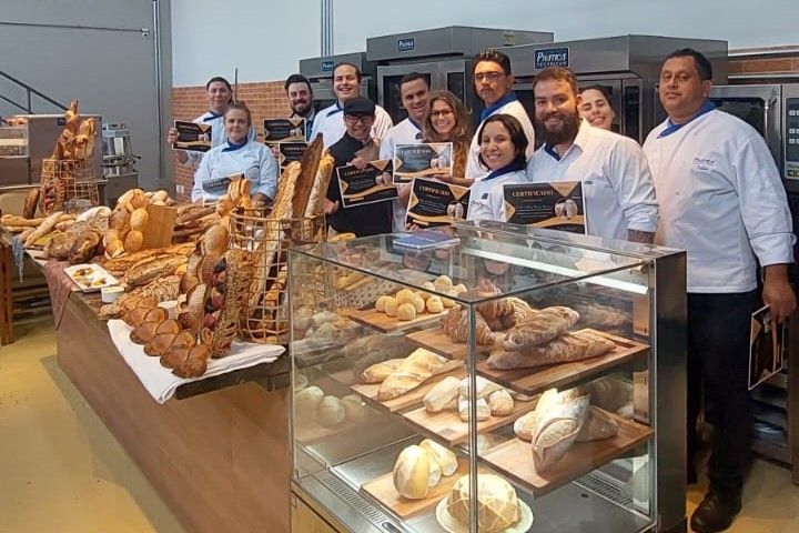 Um grupo de pessoas está em frente a uma vitrine cheia de pão.