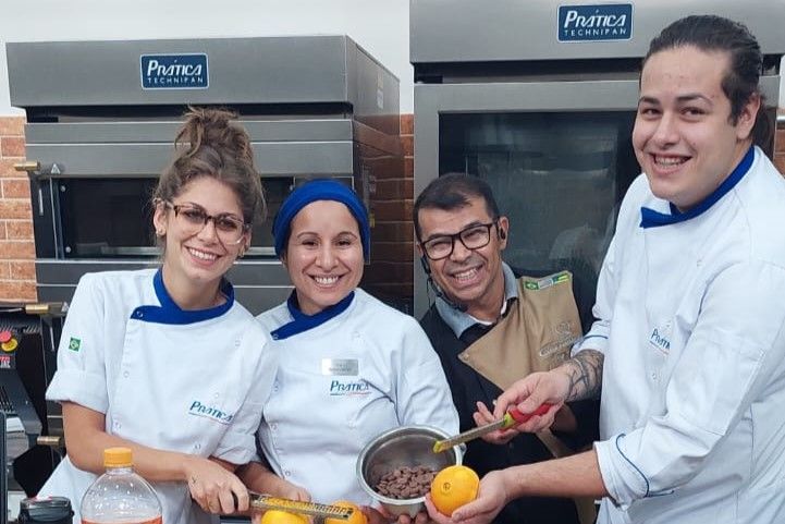 Um grupo de pessoas em pé, uma ao lado da outra, em uma cozinha