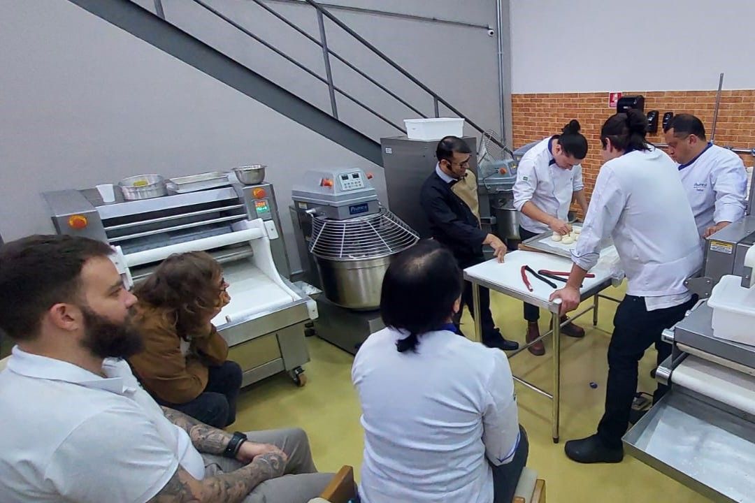Um grupo de pessoas está sentado ao redor de uma mesa na cozinha.